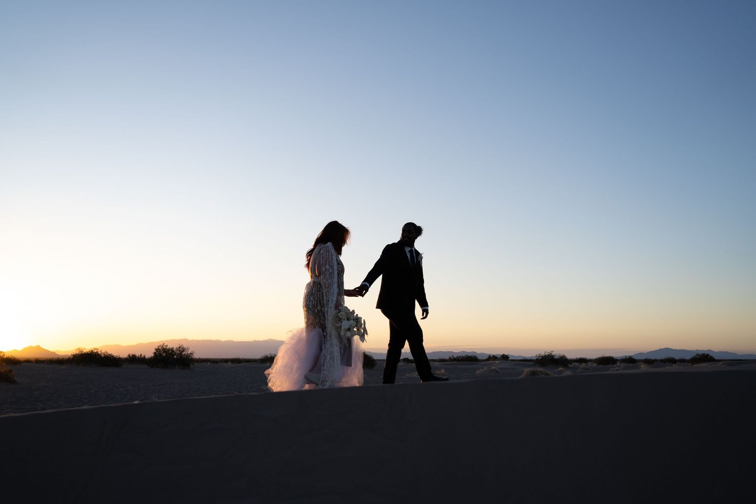 Couple walks on the Nevada desert during Sunrise. Photo by Wornden Ly