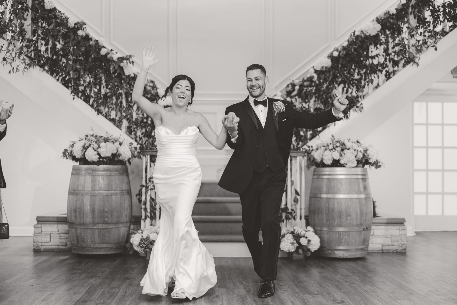 Black and white photo of bride and groom making grand entrance at wedding reception.