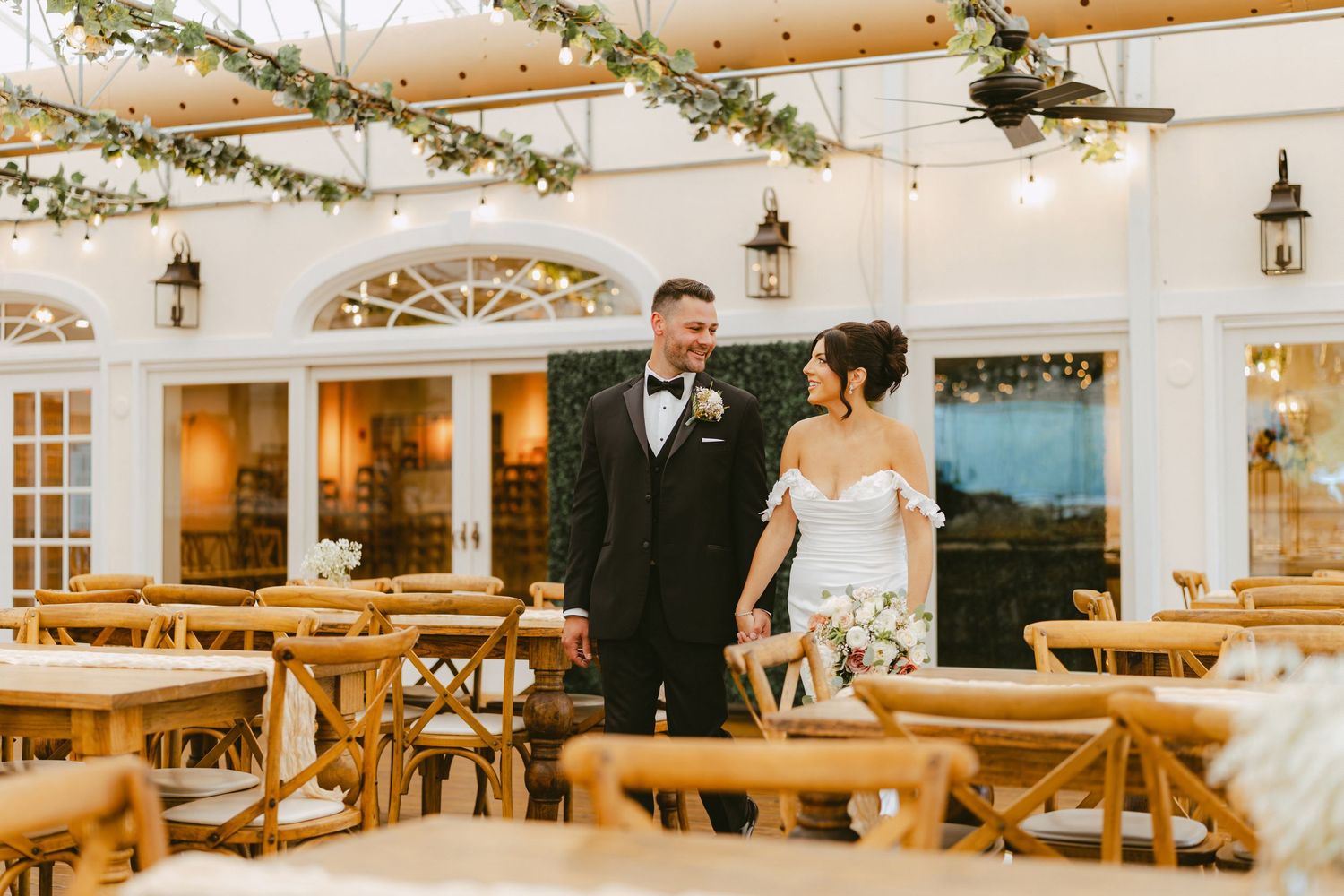 Bride and groom sharing a romantic moment in an elegant sunlit wedding reception hall.