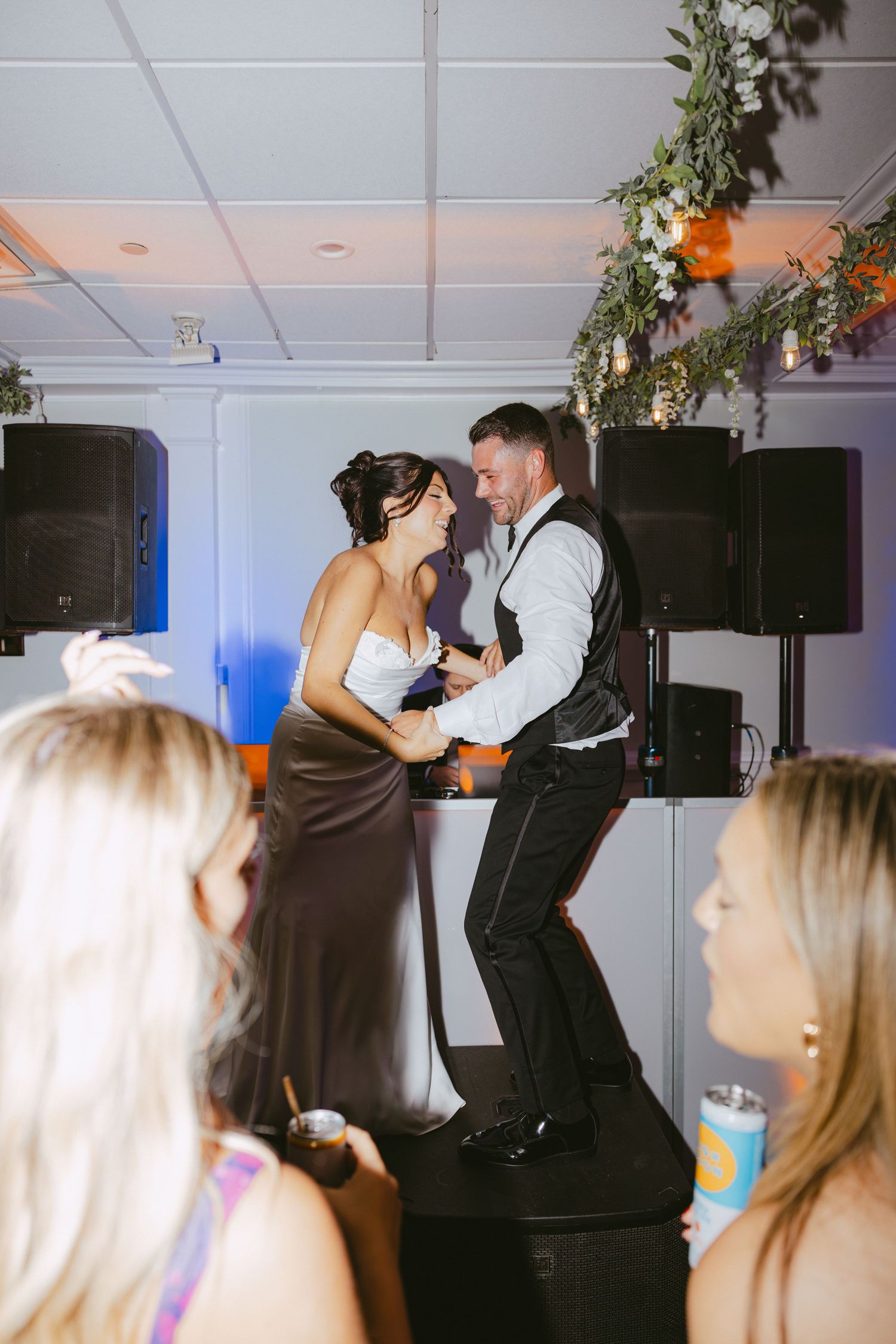 Bride and groom dance energetically on stage at their lively wedding reception.