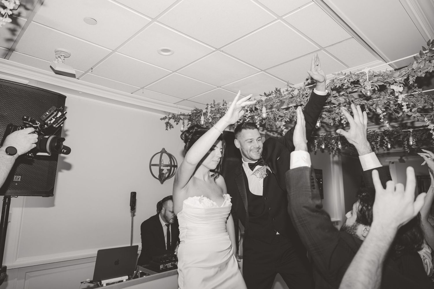 Black and white photo of bride and groom celebrating joyfully on the dance floor.