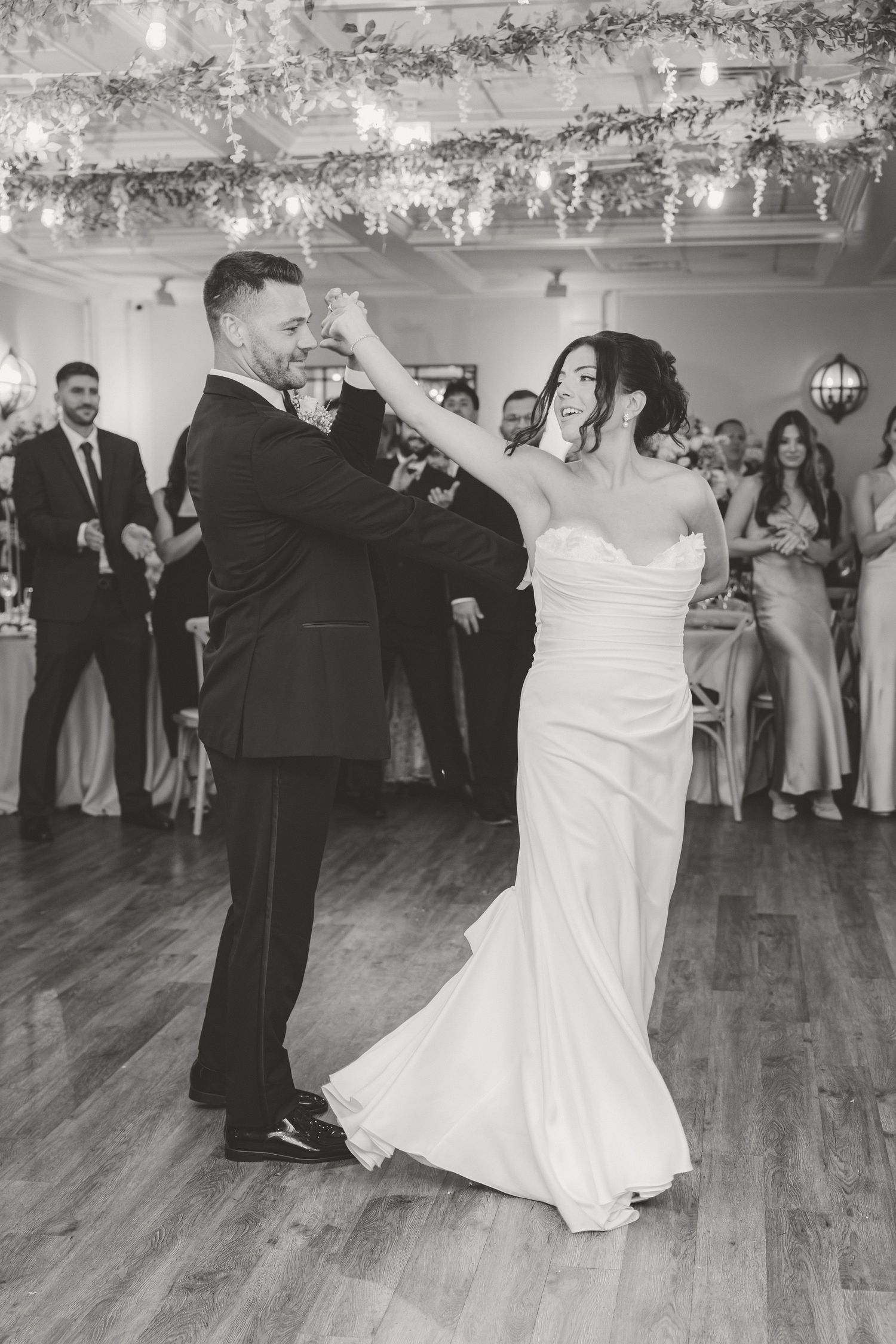 Black and white photo of bride and groom sharing their first dance at wedding reception.