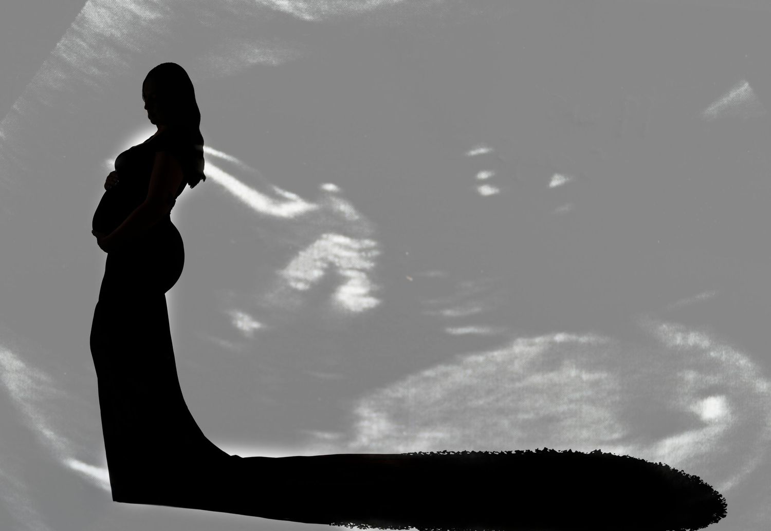 Silhouette of a pregnant woman standing against an ultrasound scan background in black and white.