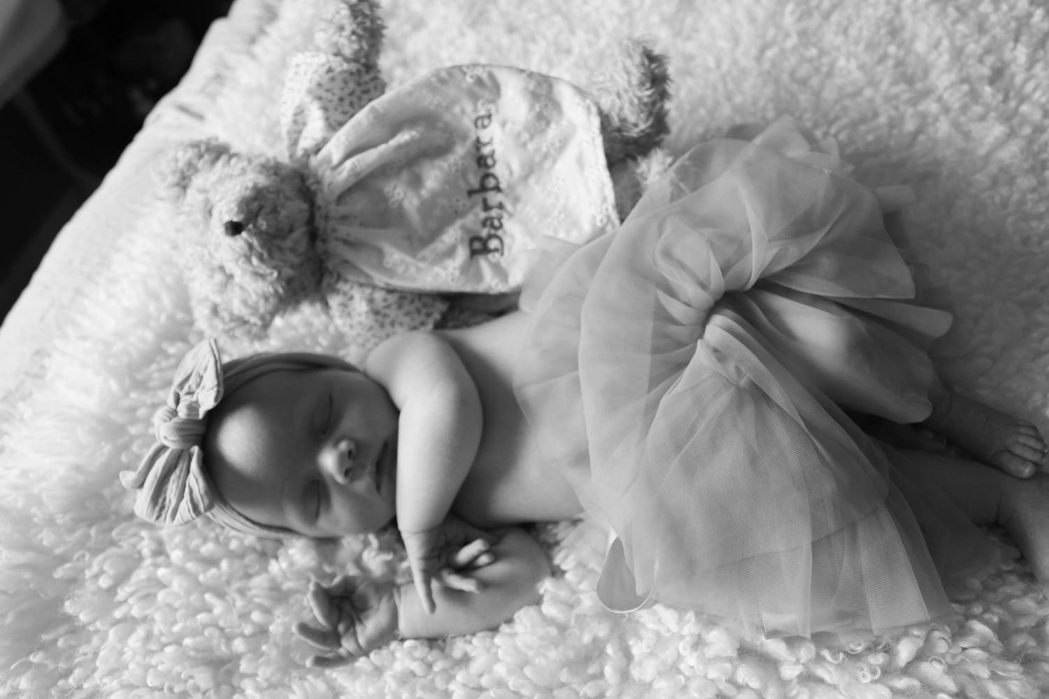 Black and white photo of newborn baby in tutu with stuffed bunny.