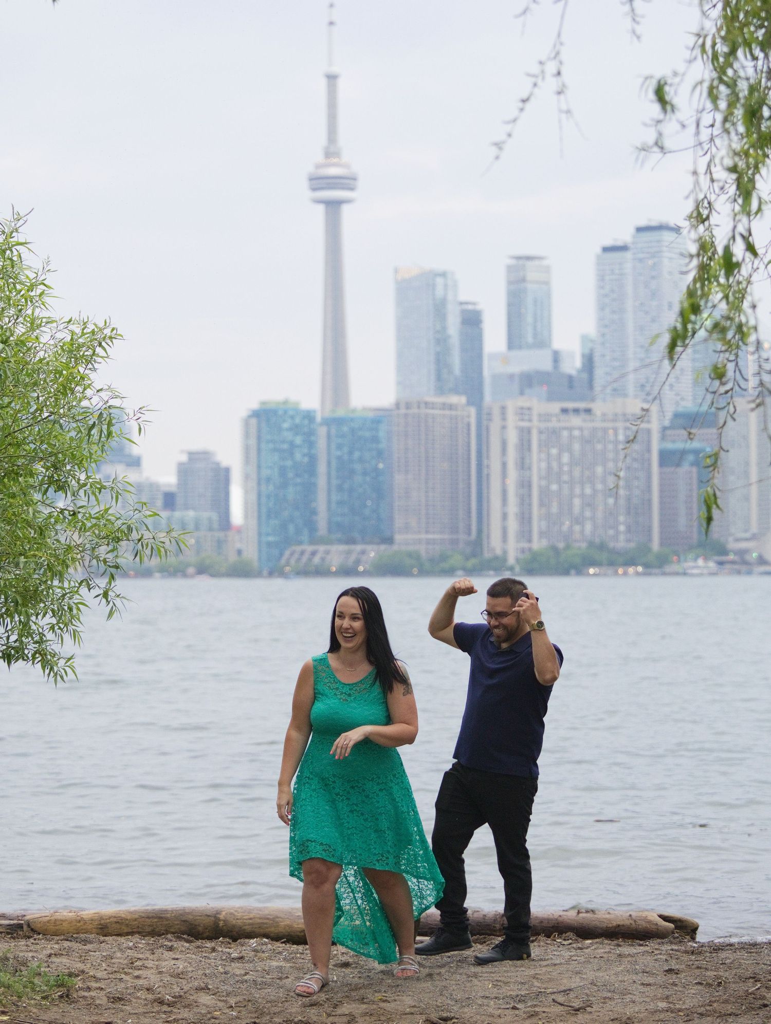 Couple dancing by Toronto waterfront with CN Tower and city skyline in background on a summer day.