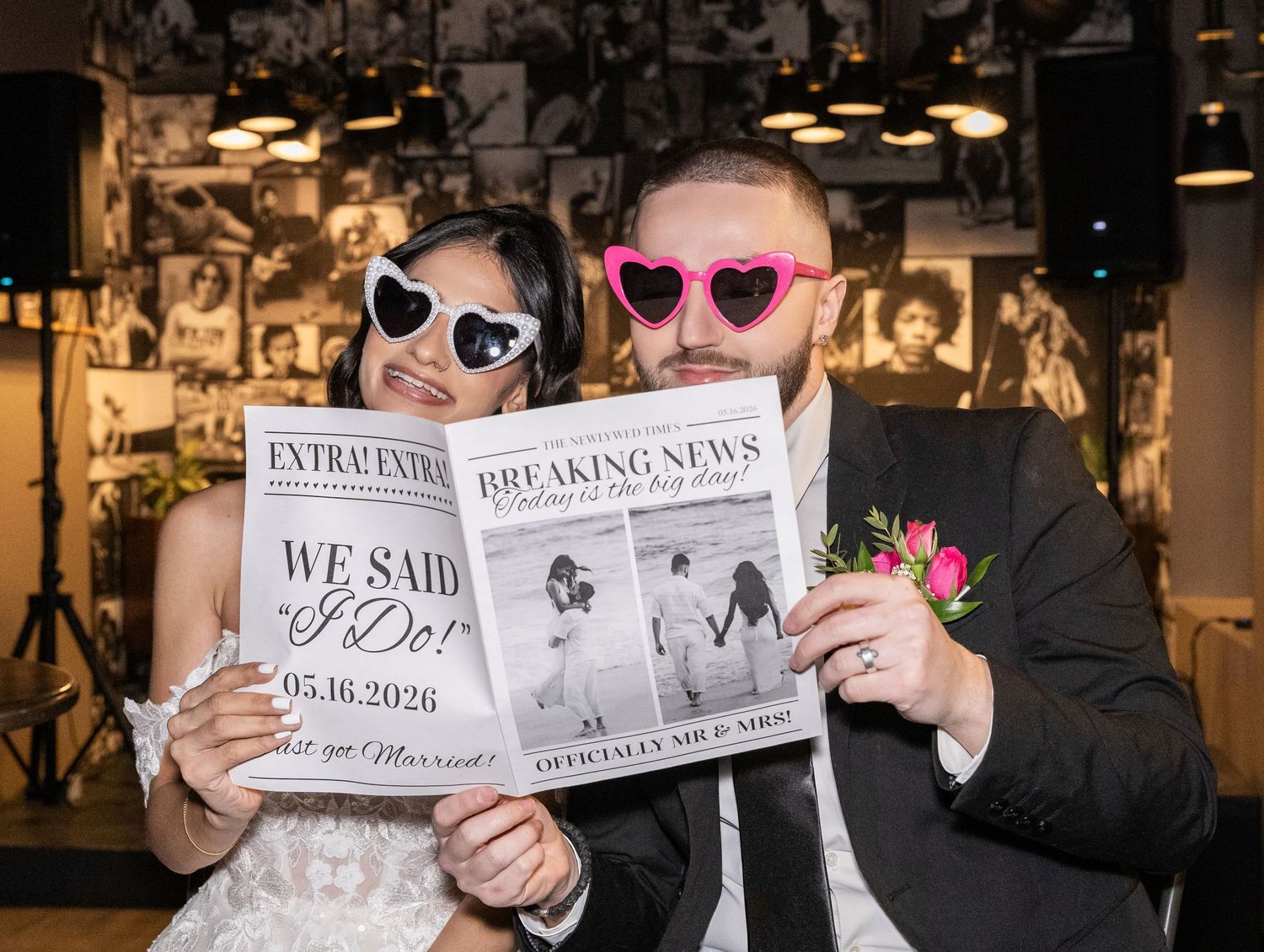 Bride and groom wear heart sunglasses holding custom wedding newspaper announcing their I Do moment.