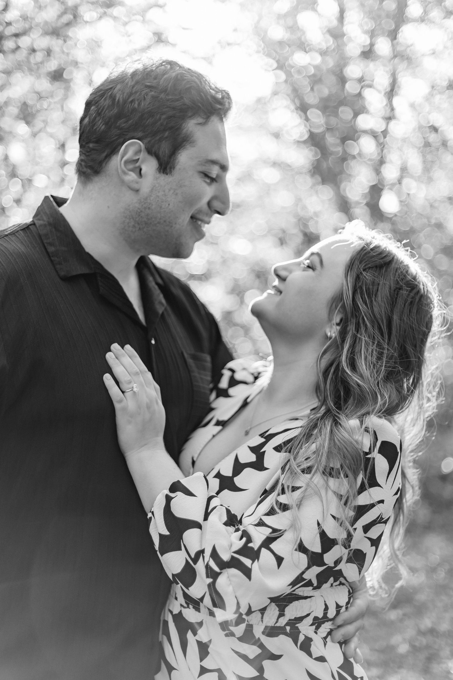 Black and white romantic couple portrait outdoors with bokeh light background in natural setting.