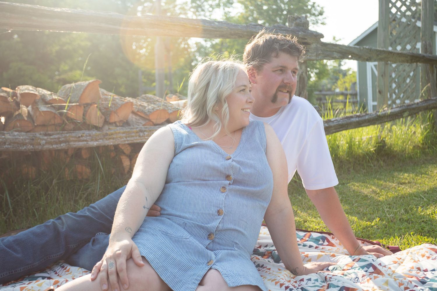 A couple relaxes together on a blanket in a sunny backyard garden.