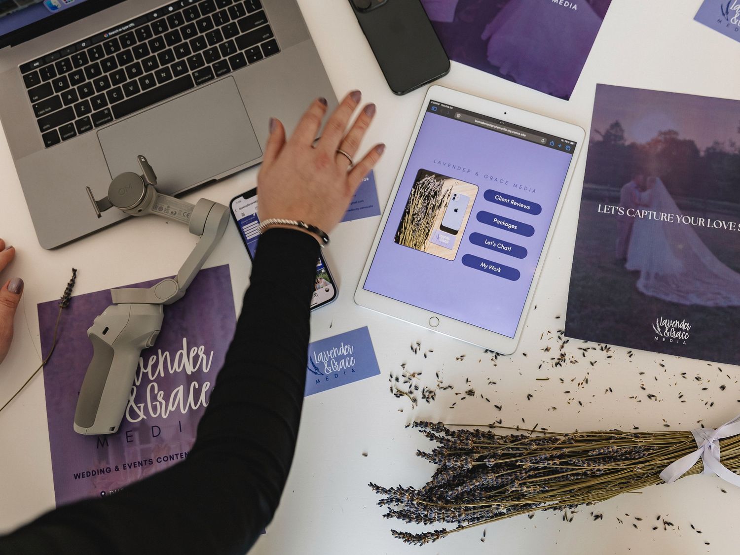 Overhead view of a wedding photography branding workspace with lavender, tablet, laptop, and purple marketing materials.