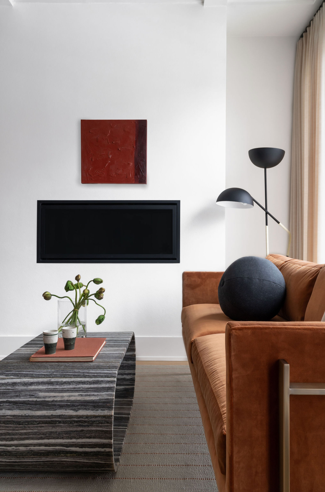 Minimalist living room with tan leather sofa, marble coffee table, linear fireplace, and arc lamp.
