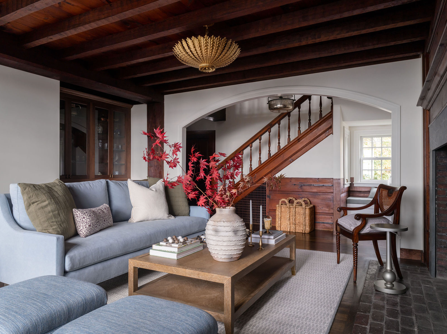 Warm living room with arched doorway, exposed wood ceiling, gray sofa, and decorative vase.