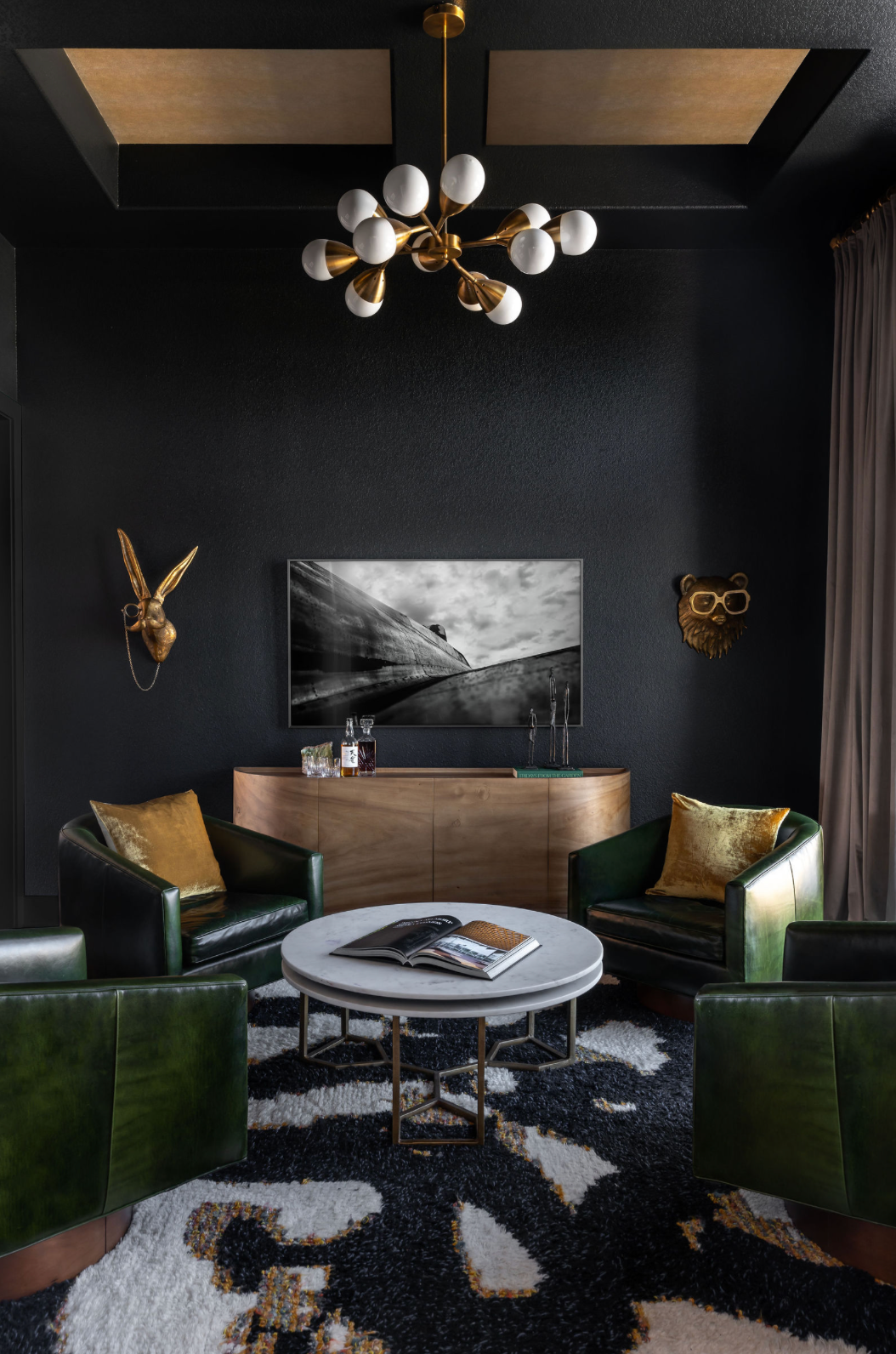 Dramatic dark lounge with green velvet chairs, gold accents, and sputnik chandelier.