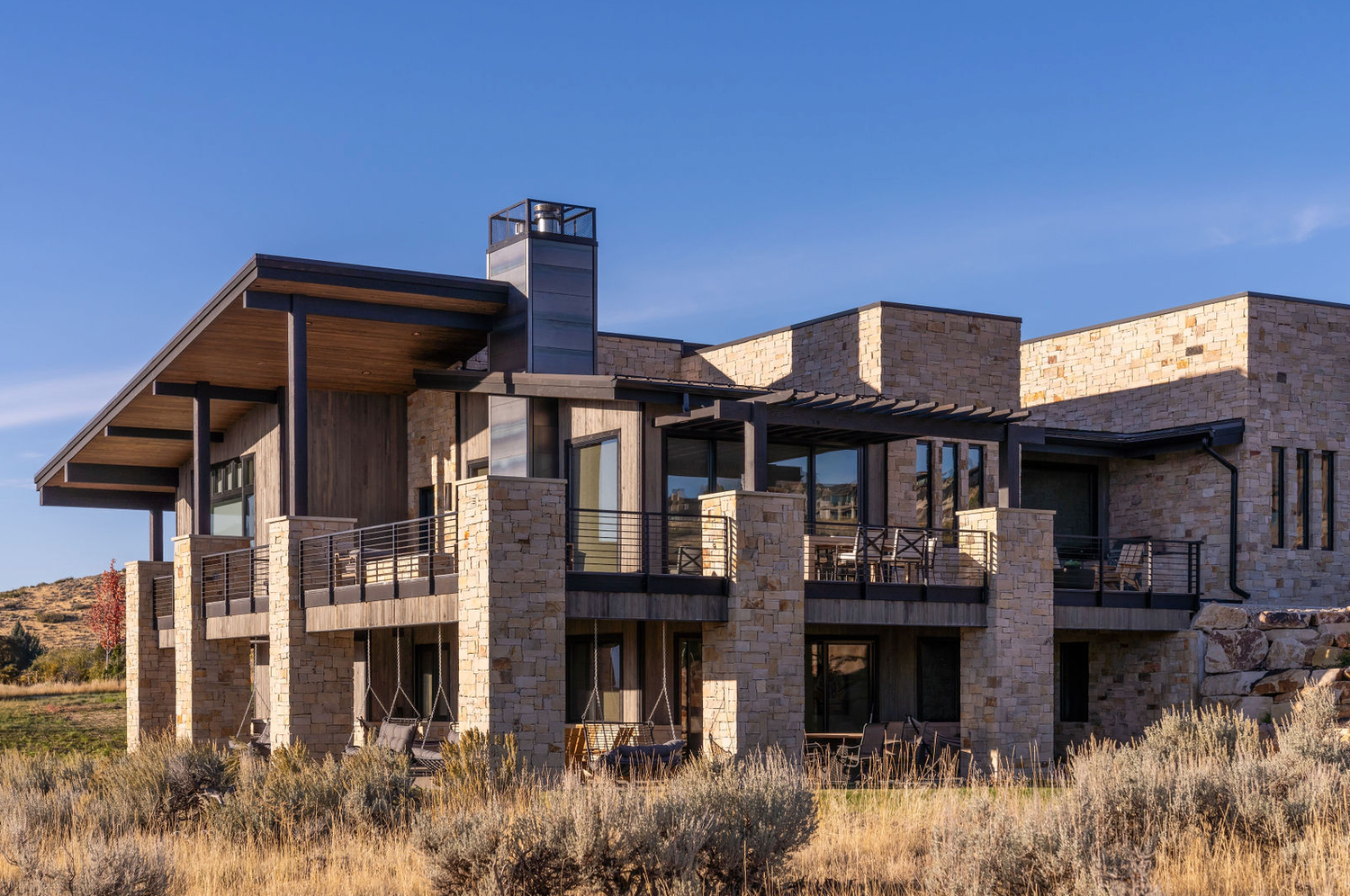 Luxury multi-level stone and wood mountain home with wraparound balconies and expansive valley views.