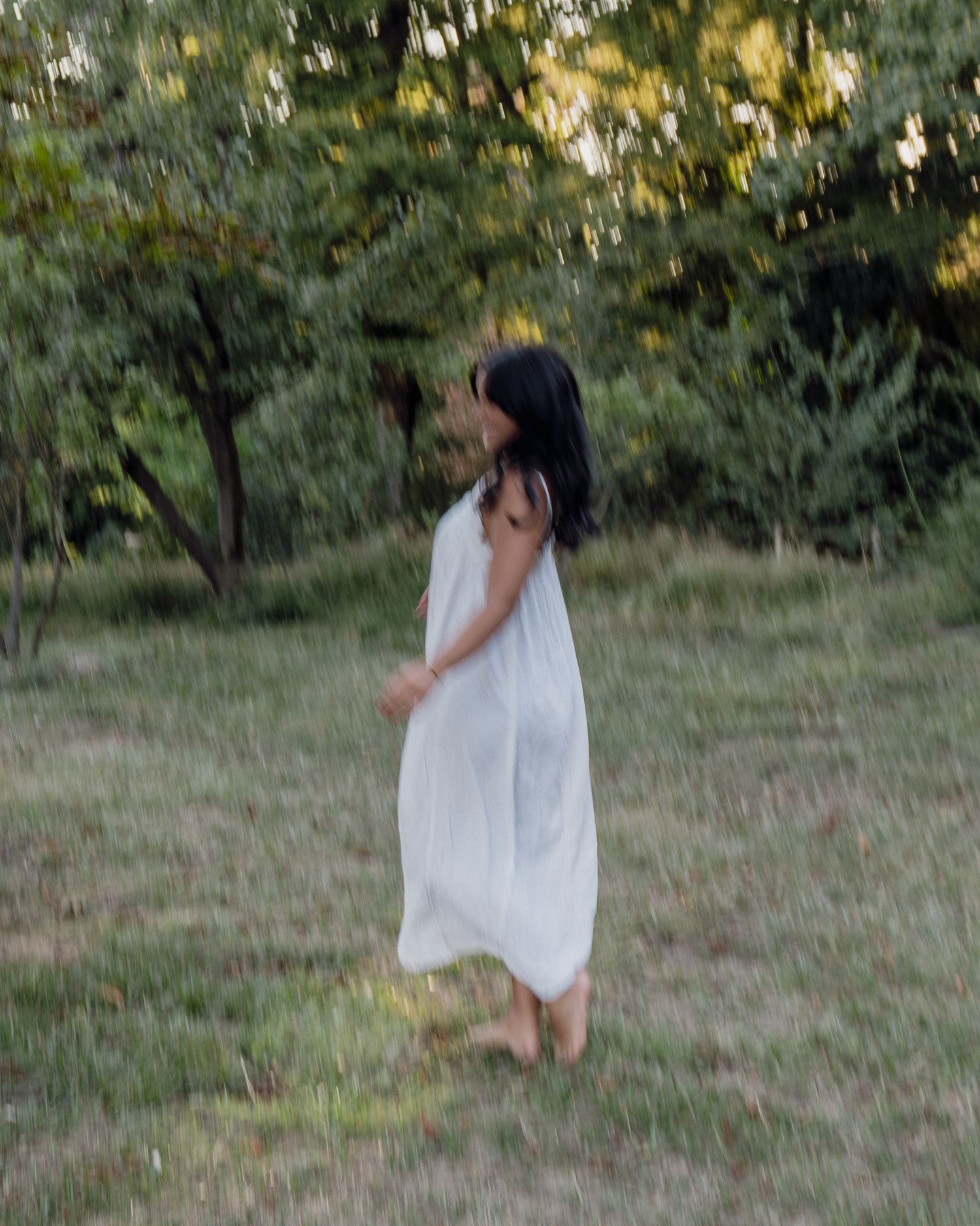 Femme en robe blanche photographiée en extérieur dans un champ arboré à Lyon.