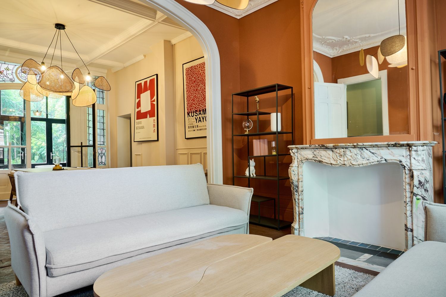 Elegant living room with white sofa, marble fireplace, arched doorway, and warm terracotta walls in a classic interior.