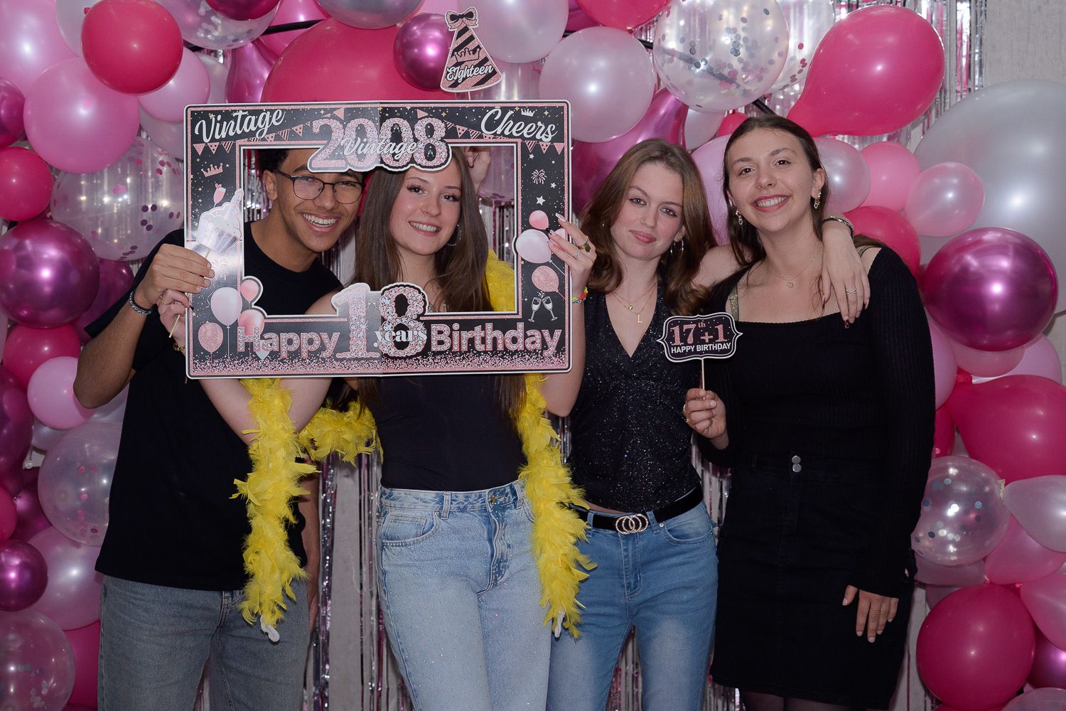 Four friends pose at a pink balloon backdrop photo booth celebrating a Happy 18th Birthday party in 2008.