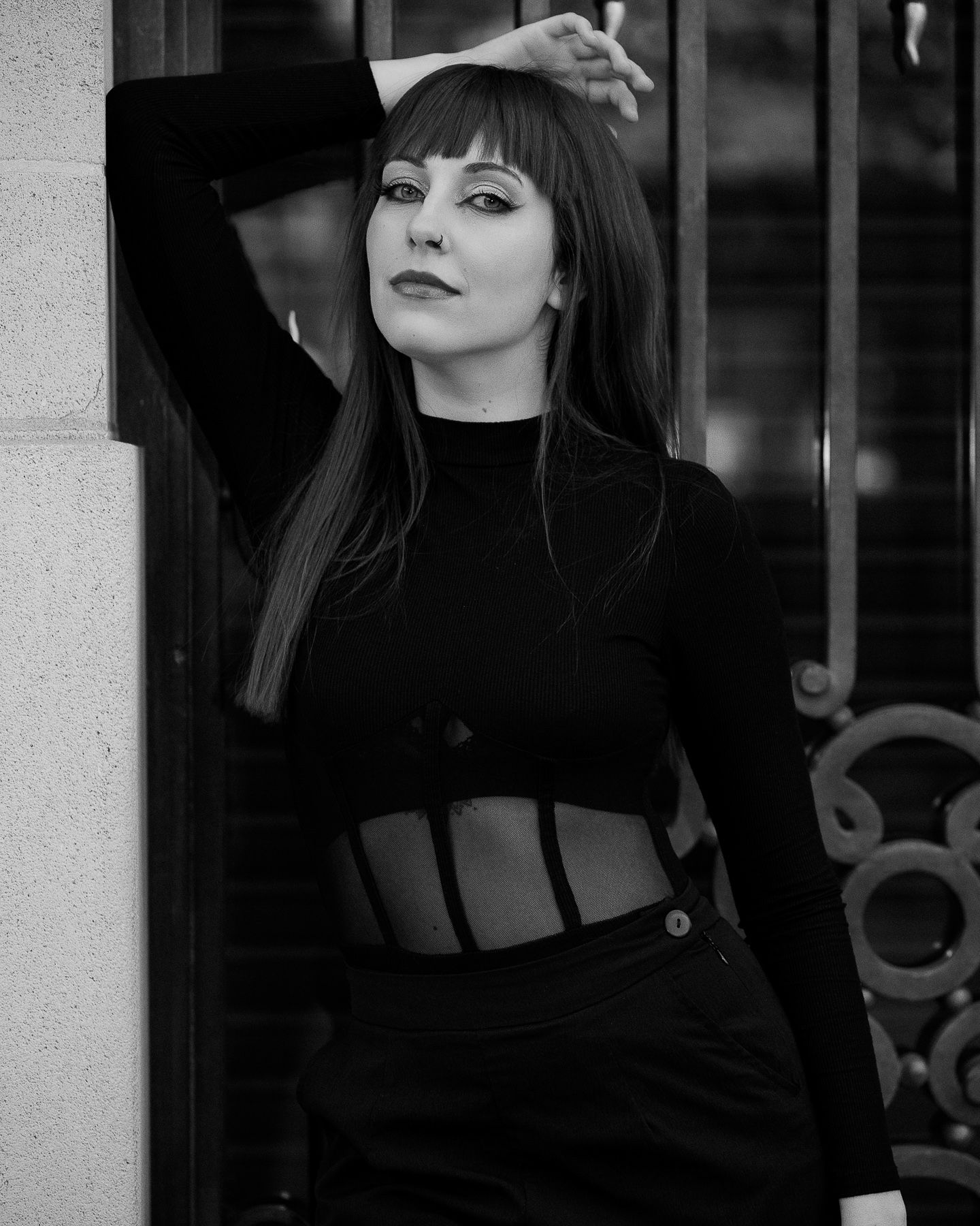 Black and white photo of a young woman in a black crop top posing against a building.