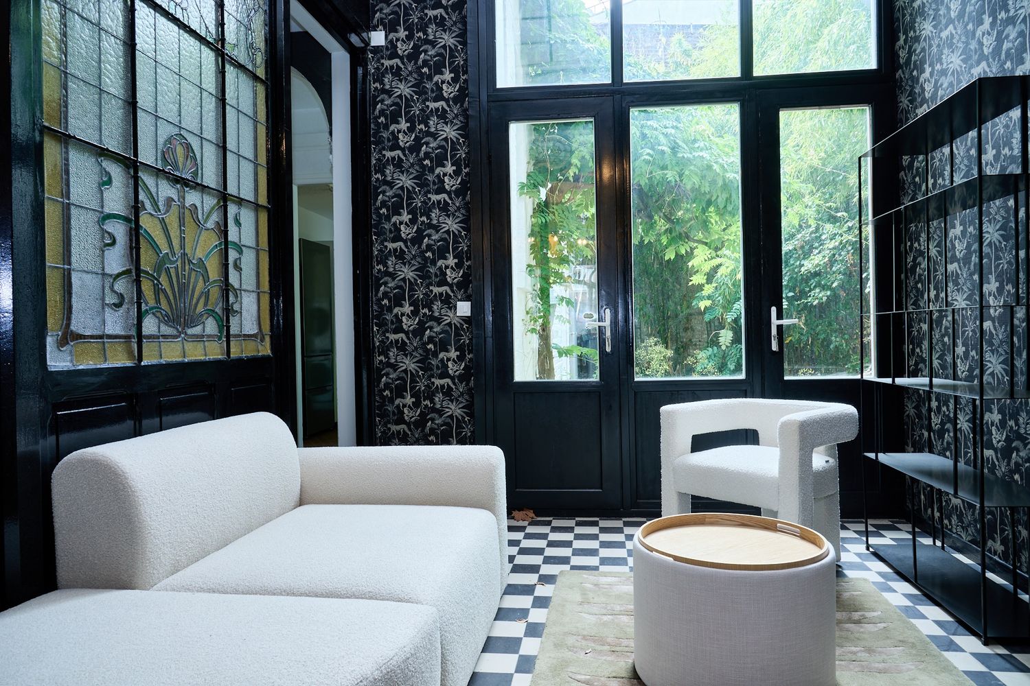 Elegant Art Nouveau lounge with white sofas, checkered floor, stained glass window, and dark floral wallpaper.