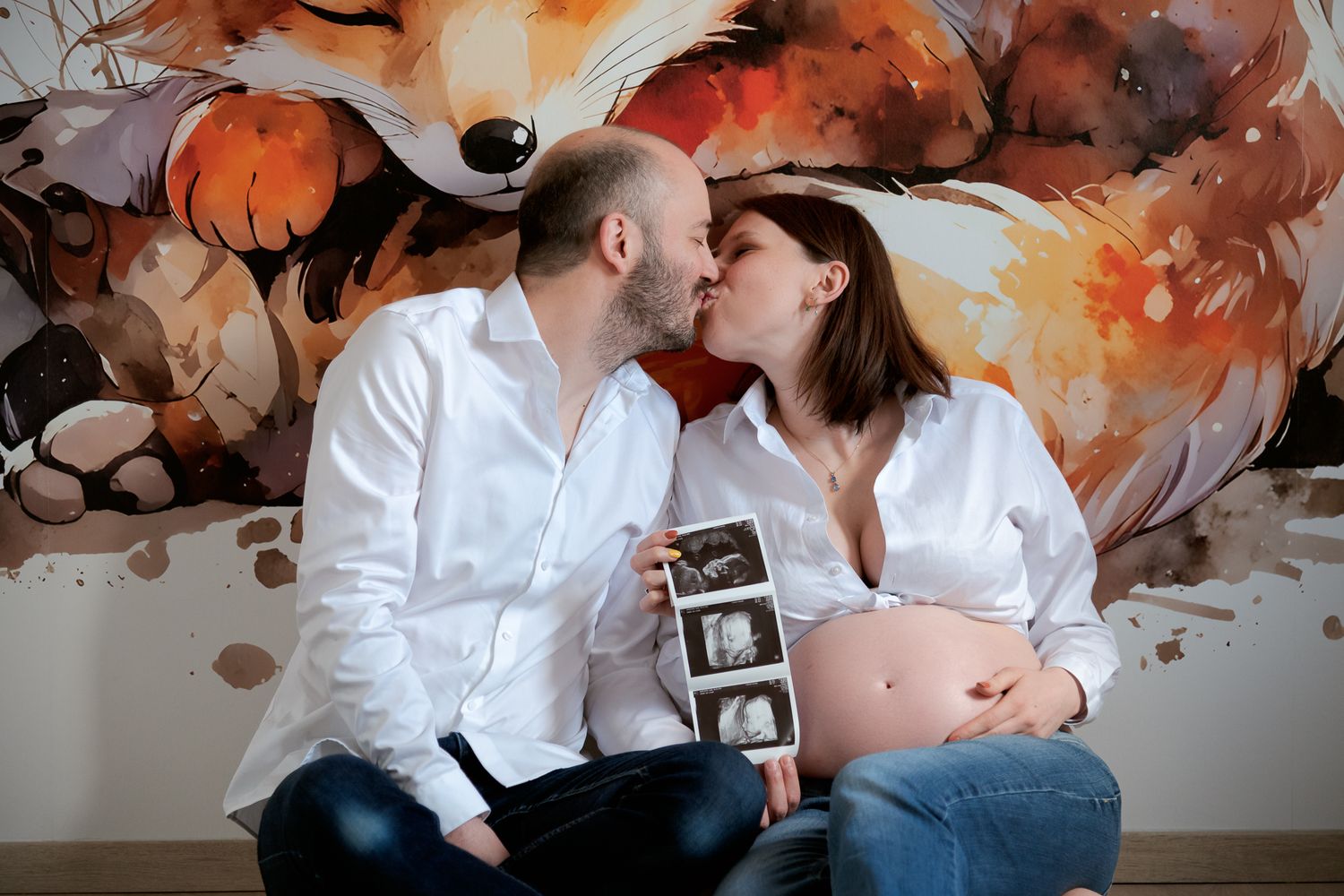 Pregnant couple kissing while holding ultrasound photos in front of colorful fox mural wall art.