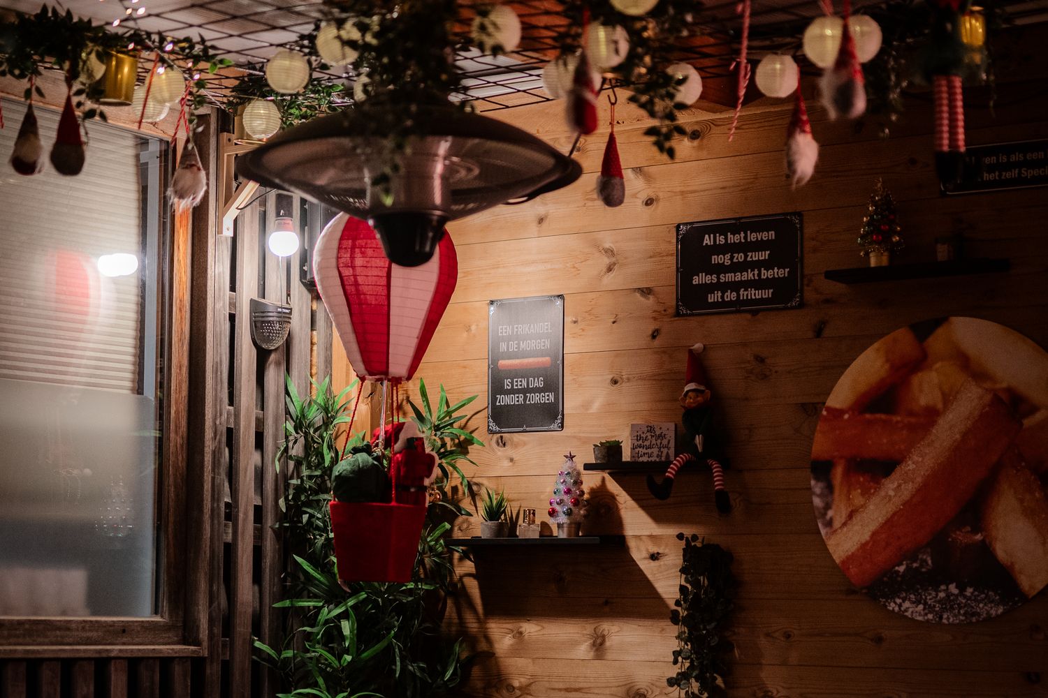 Cozy wooden chalet interior with hanging lanterns, hot air balloon decor, plants, and warm ambient lighting.