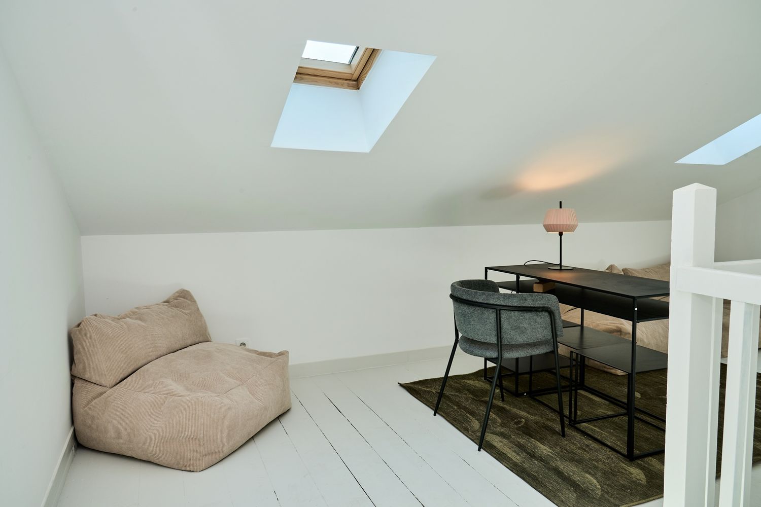 Bright attic loft space with skylight, bean bag chair, and modern desk setup.
