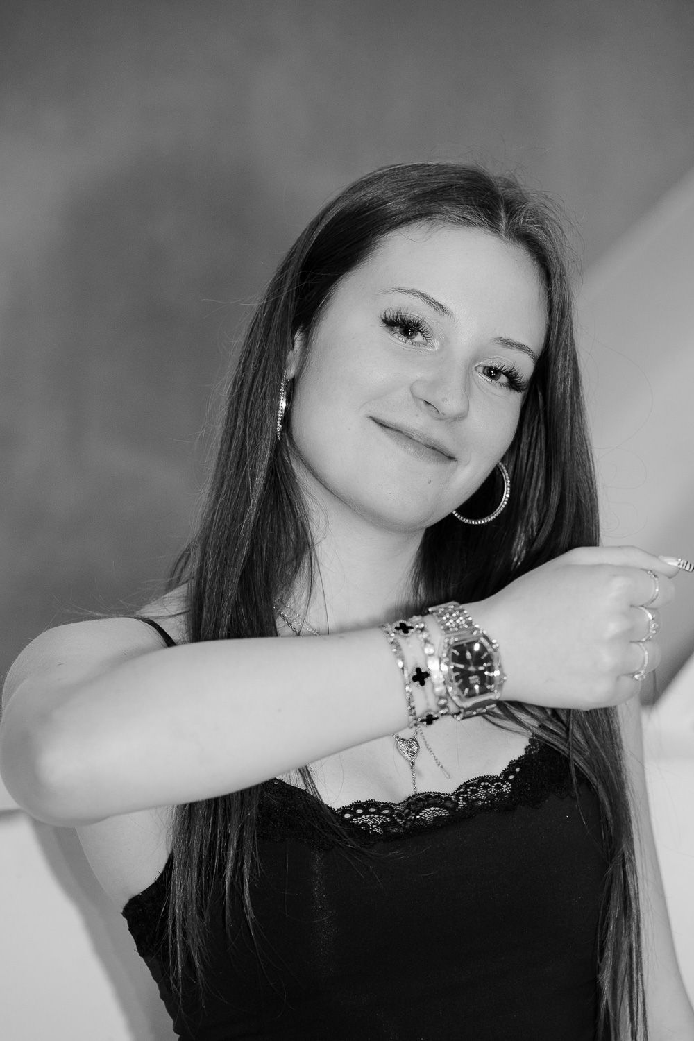 Black and white portrait of a young woman with long hair showcasing her watch and bracelets accessories.