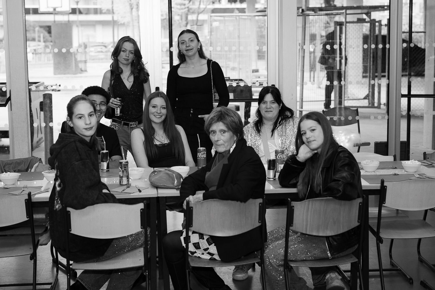 Black and white photo of a group of eight women posing together at a restaurant table.