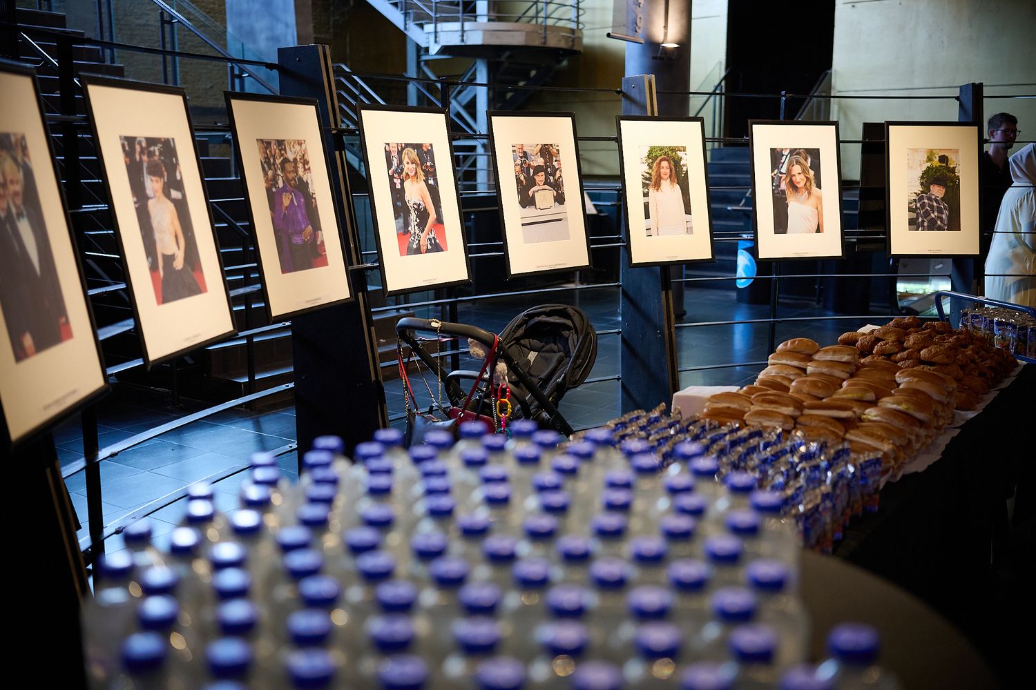 Framed artwork display at an elegant event venue with bottles and bread rolls arranged on a catered buffet table.