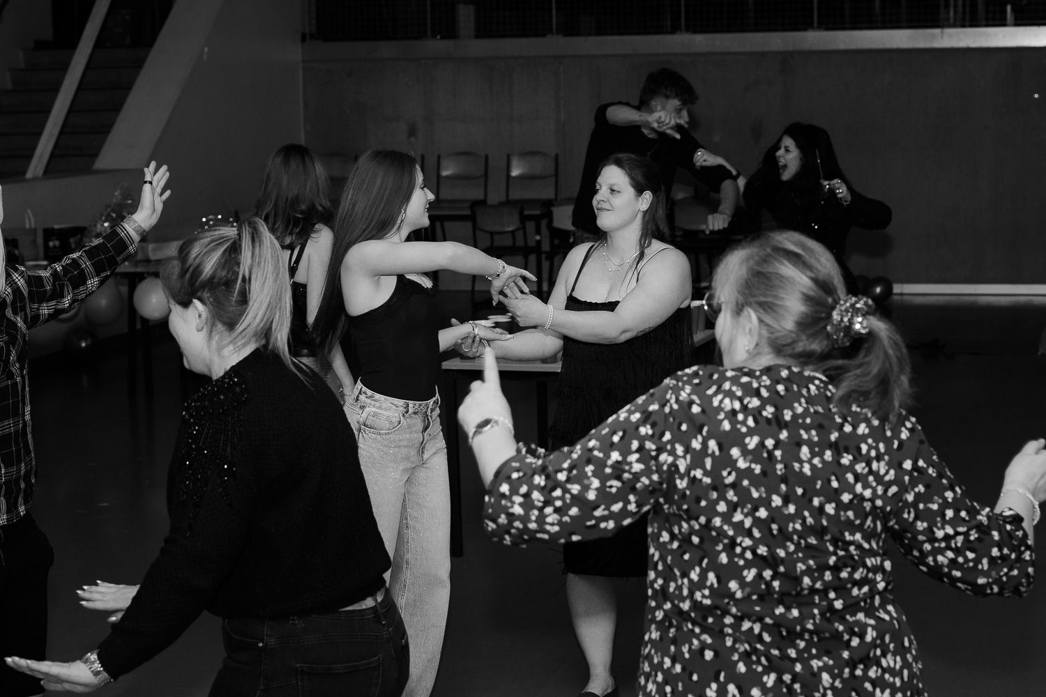 Black and white photo of a group of young women dancing and having fun at an indoor party event.