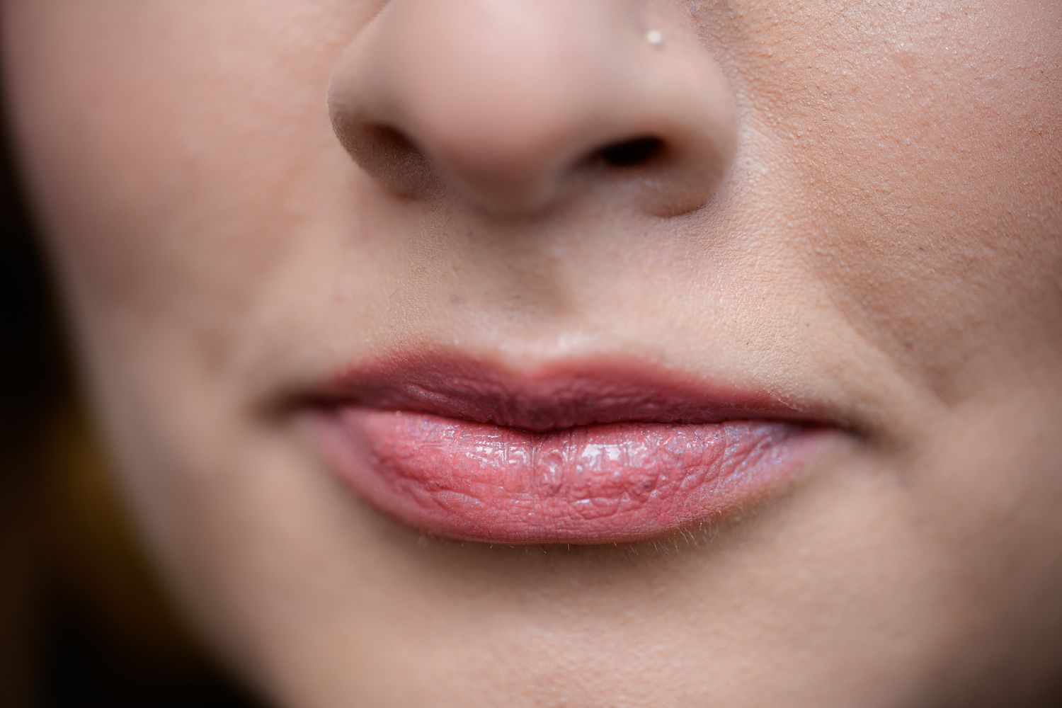 Close-up of a woman's lips and nose showing natural pink lips and clear skin.