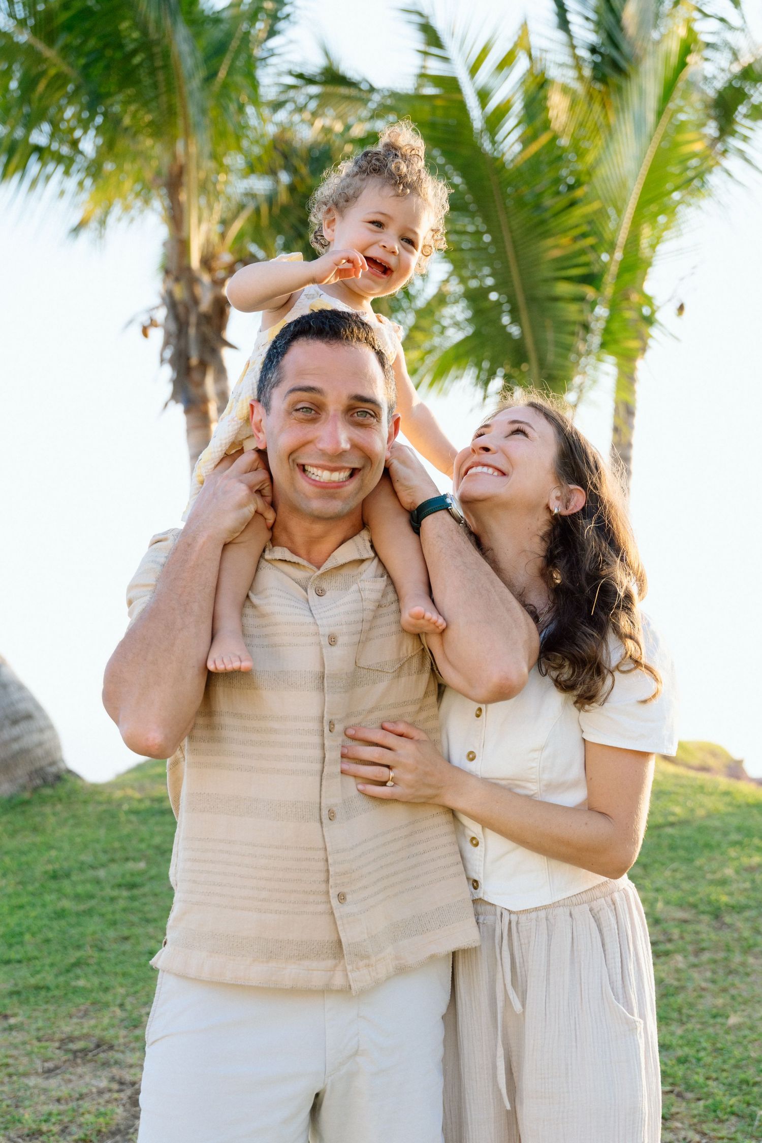 Mom and dad hugging and holding their daughter during a family session in Puerto Vallarta Mexico — Marina Pochekina photography