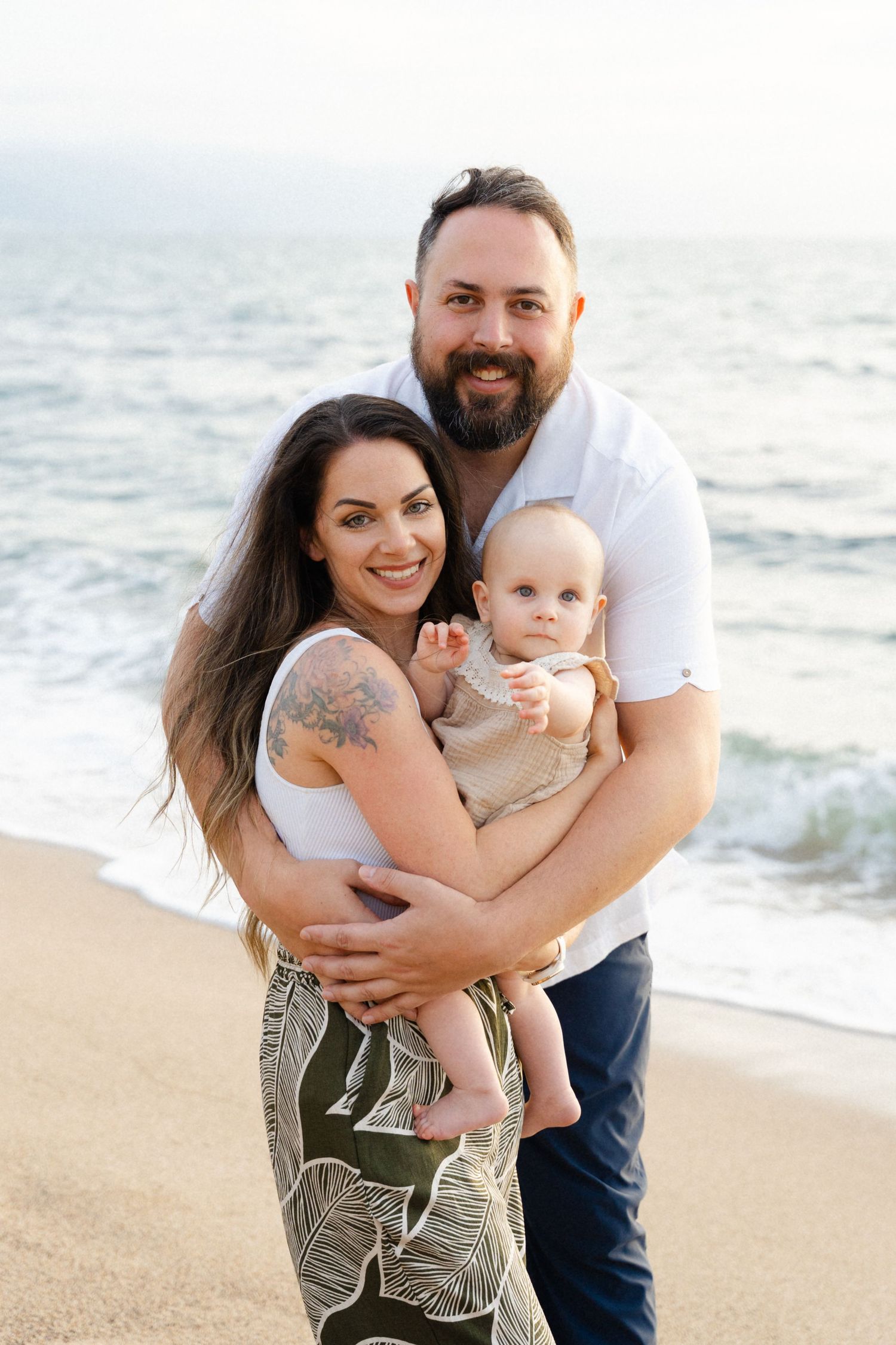 Dad hugging mom while she holds their baby during a family photo session in Punta Mita Mexico — Marina Pochepkina Photography
