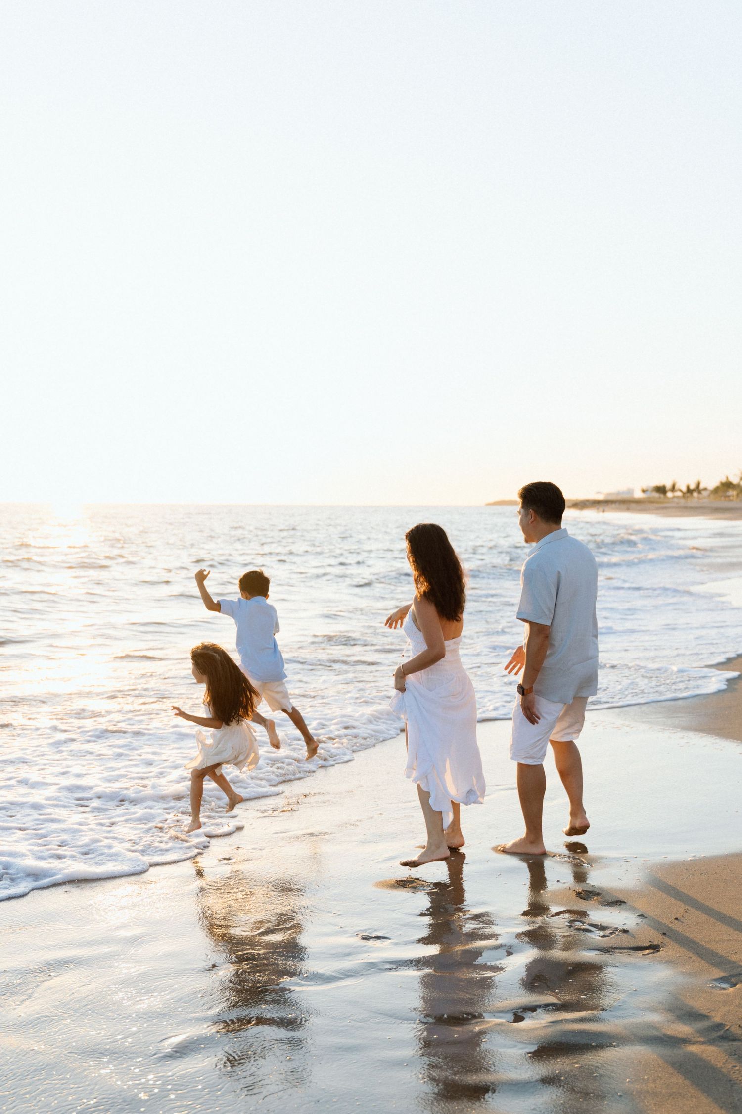 Family of four splashing and running into the ocean waves in Punta Mita Mexico — Marina Pochepkina Photography