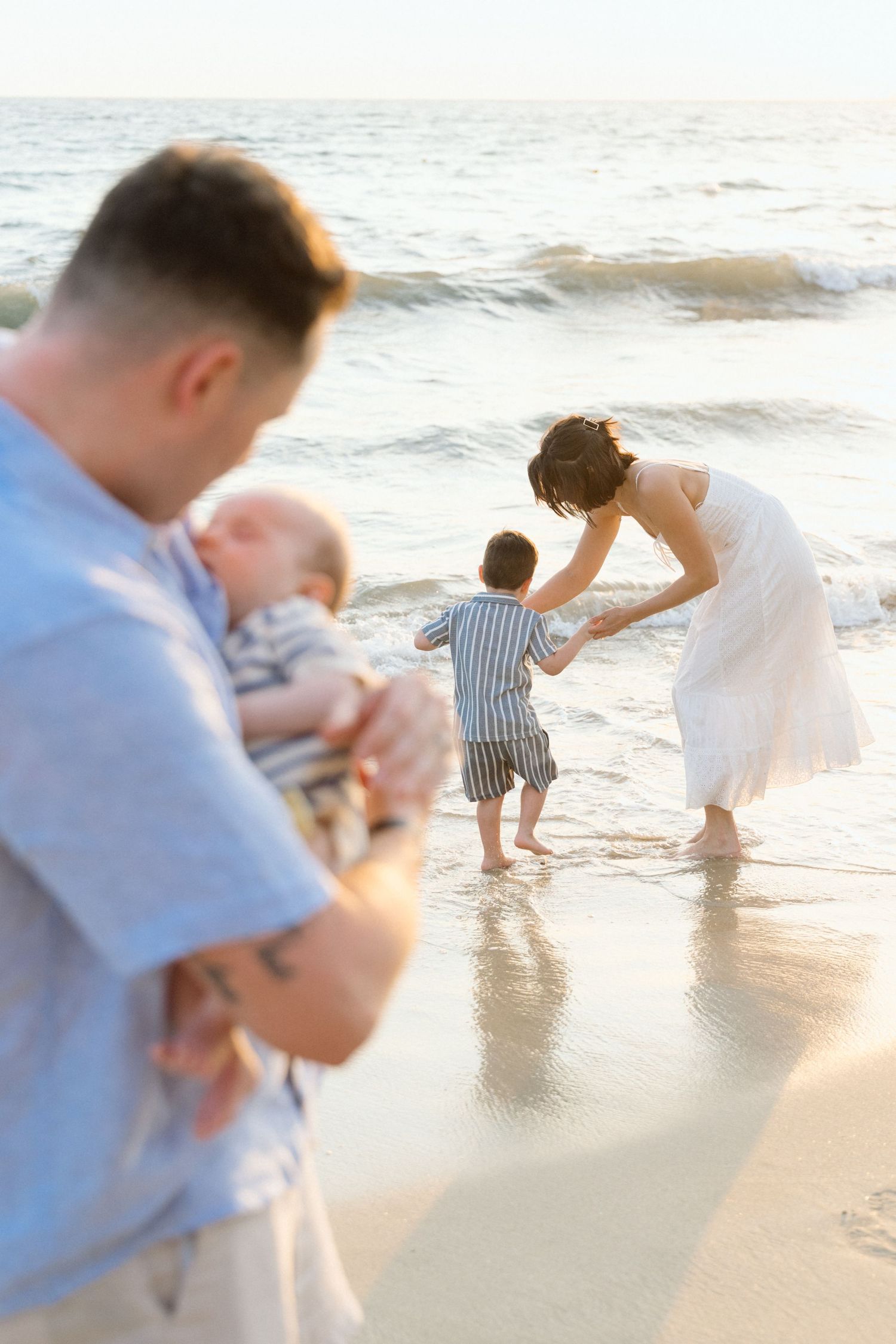 Dad holding baby while mom plays with older son on the beach in Puerto Vallarta Mexico — Marina Pochepkina Photography