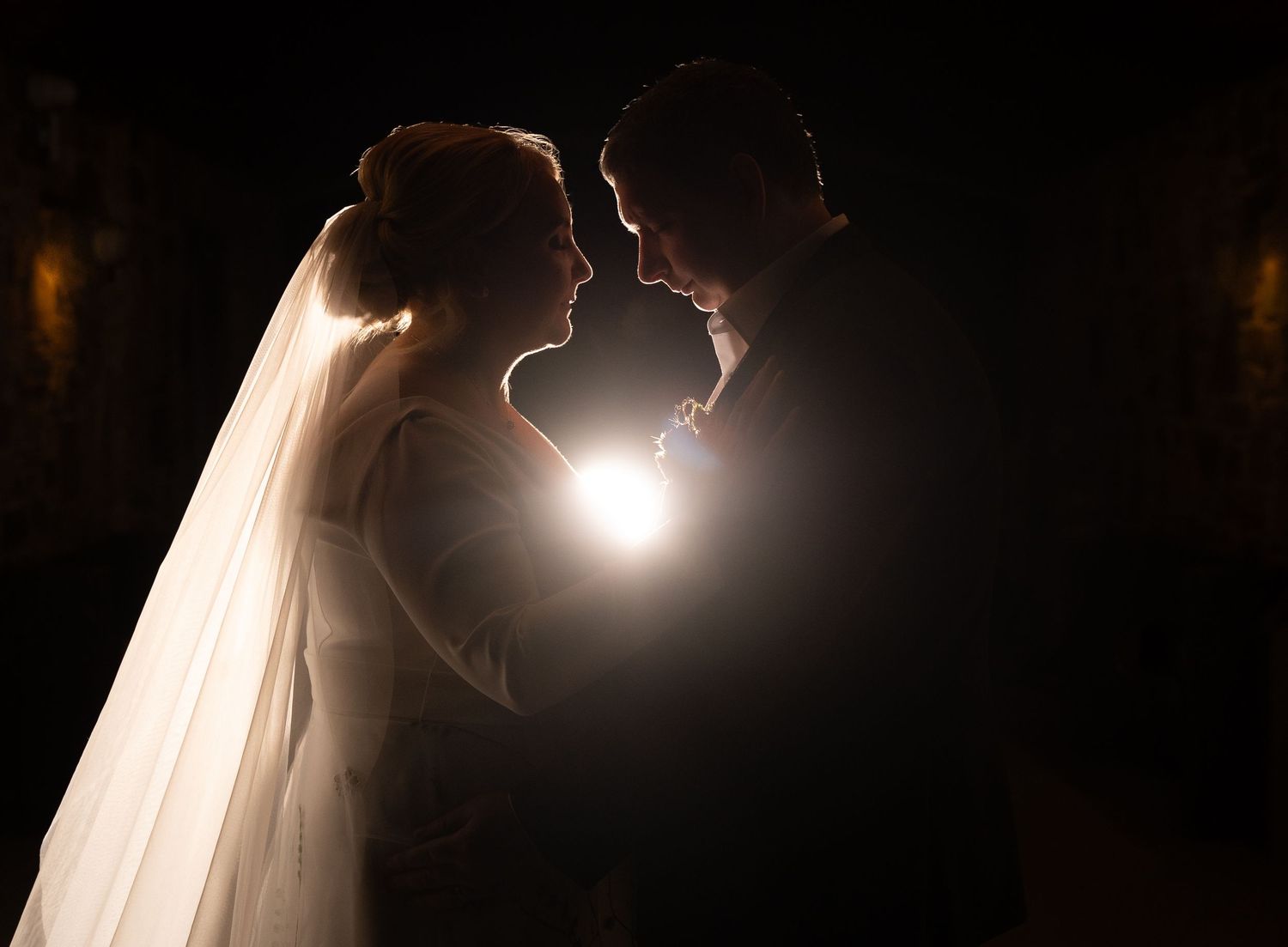 Romantic wedding couple silhouette with glowing backlight, bride in veil and groom facing each other in tender moment at Bellinter house.