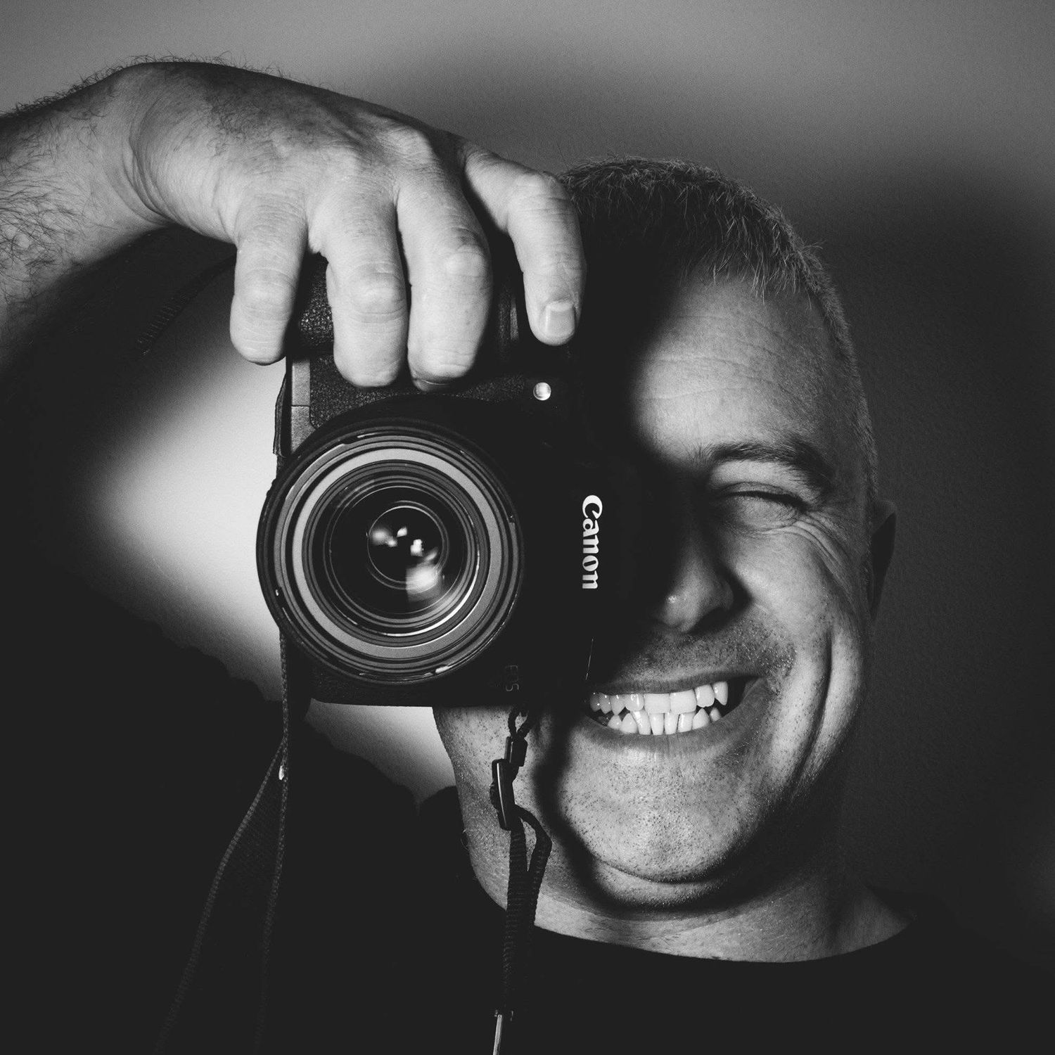 Black and white close-up shots of photographers taking pictures with digital cameras in dramatic lighting.