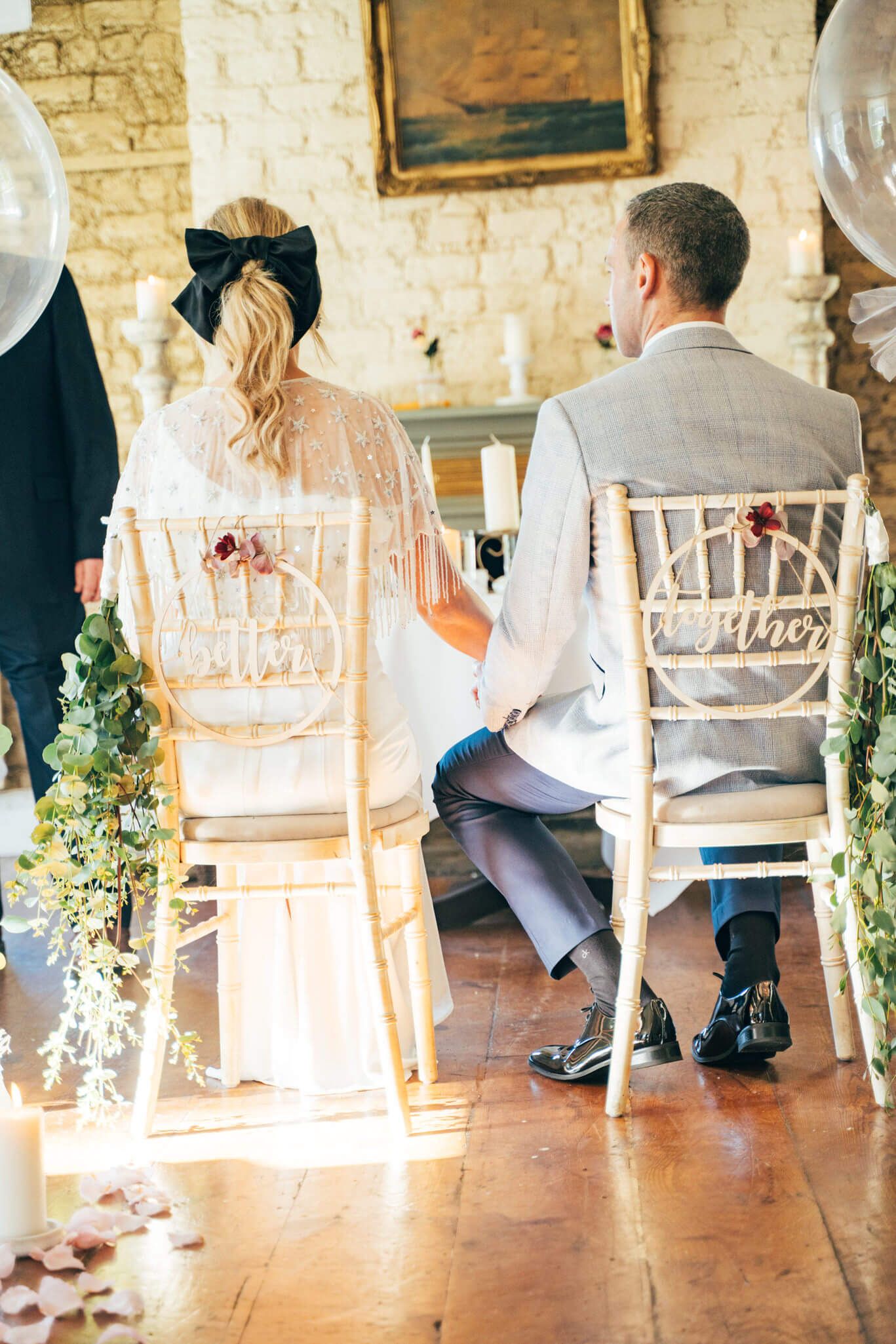 Bride with a black bow in her hair and groom sit holding hands at the Anglers rest Dublin photo by AK wedding photography and videography.