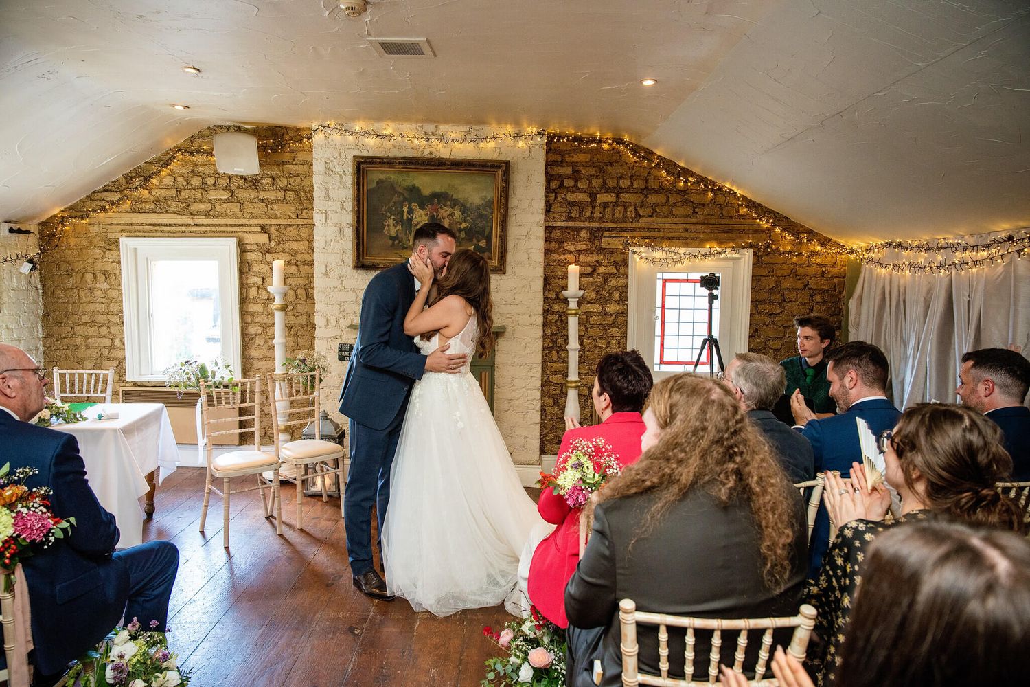 Bride in white gown and groom in navy suit kiss during wedding ceremony inside The Anglers Rest Dublin photo by AK wedding photography.