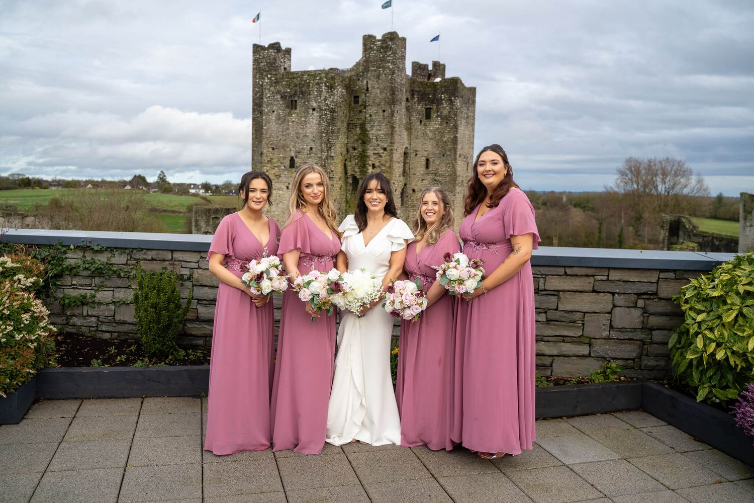 Bridal party on Trim castle hotel roof in front of historic Trim castle photo by AK wedding photography and videography.