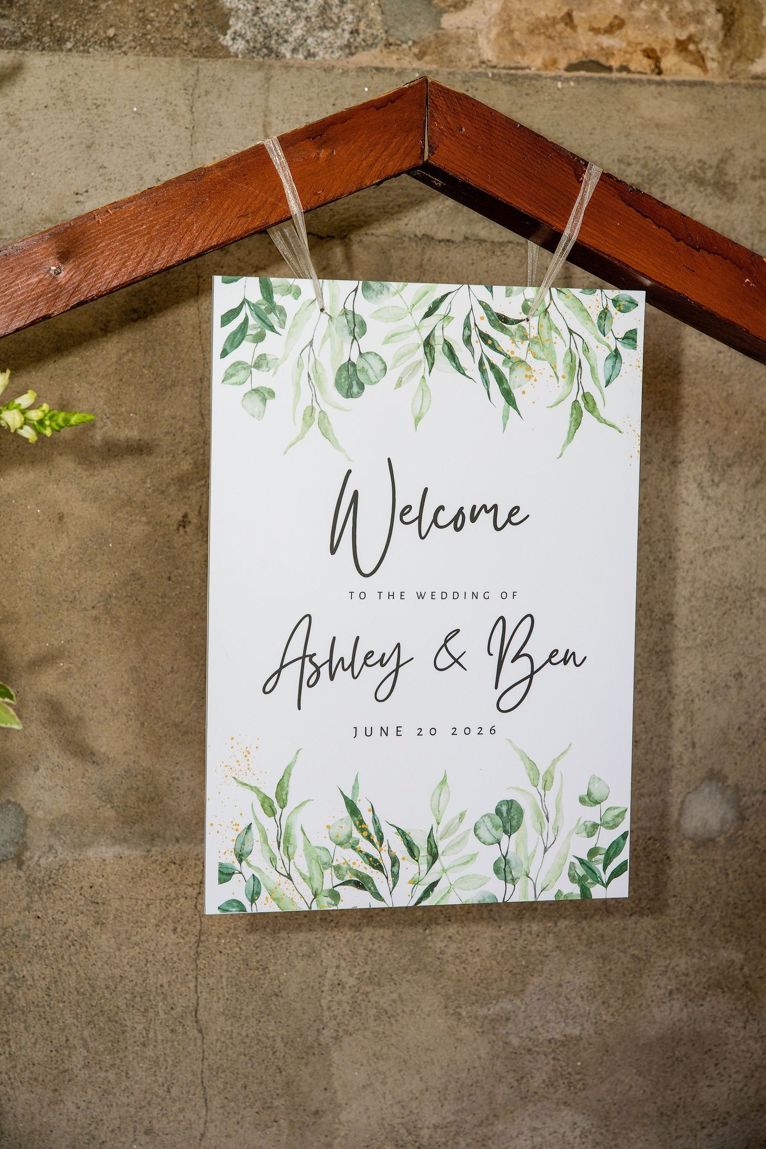 Wedding welcome sign for Ashley & Ben on June 20, 2024, featuring elegant greenery botanical design hanging on wooden frame.