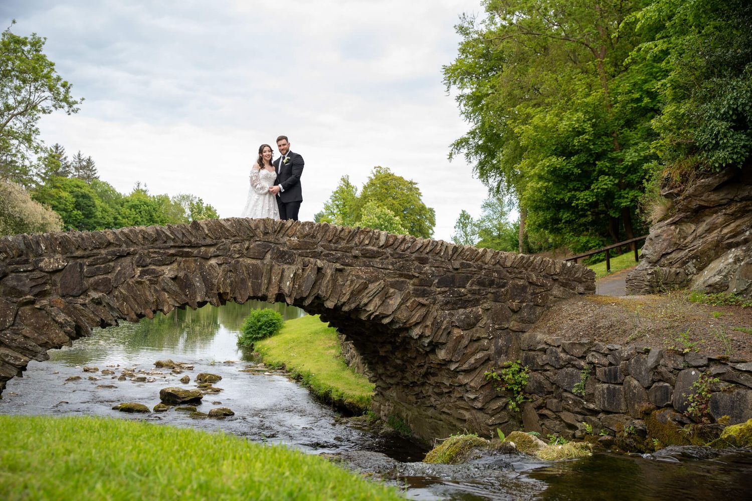 Bride and groom pose together on an old stone arch at Druids glen photo by AK wedding photography and videography.