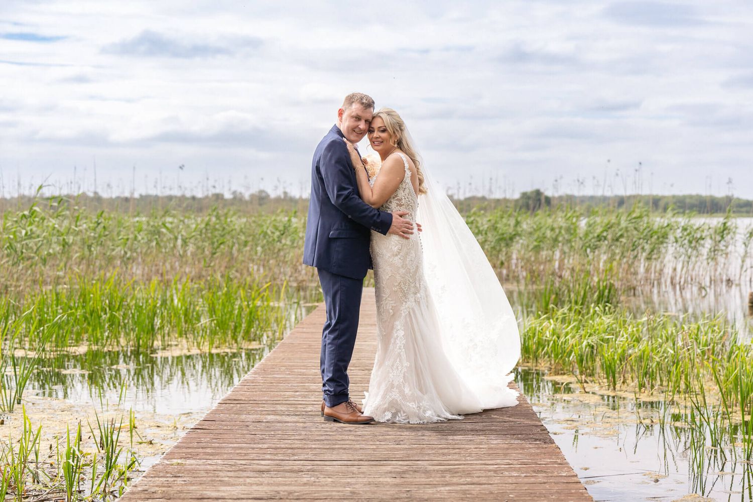 Bride  and groom embrace on a wooden boardwalk at Bloomfield house Mullingar - photo by AK wedding photography and videography.