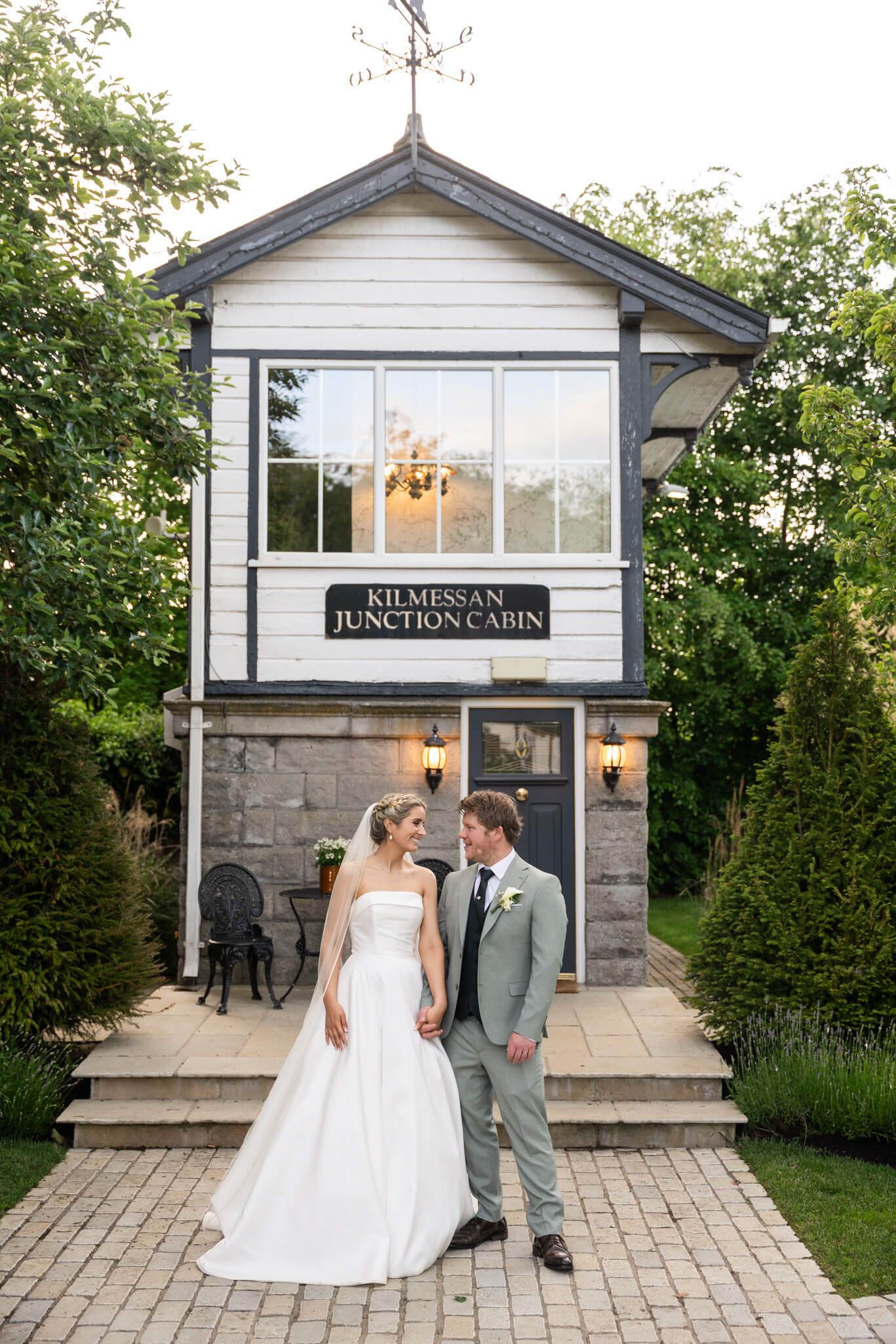 Bride  and groom stand hand in hand outside the Kilmessan Junction Cabin wedding venue photo by AK wedding photography and videography.