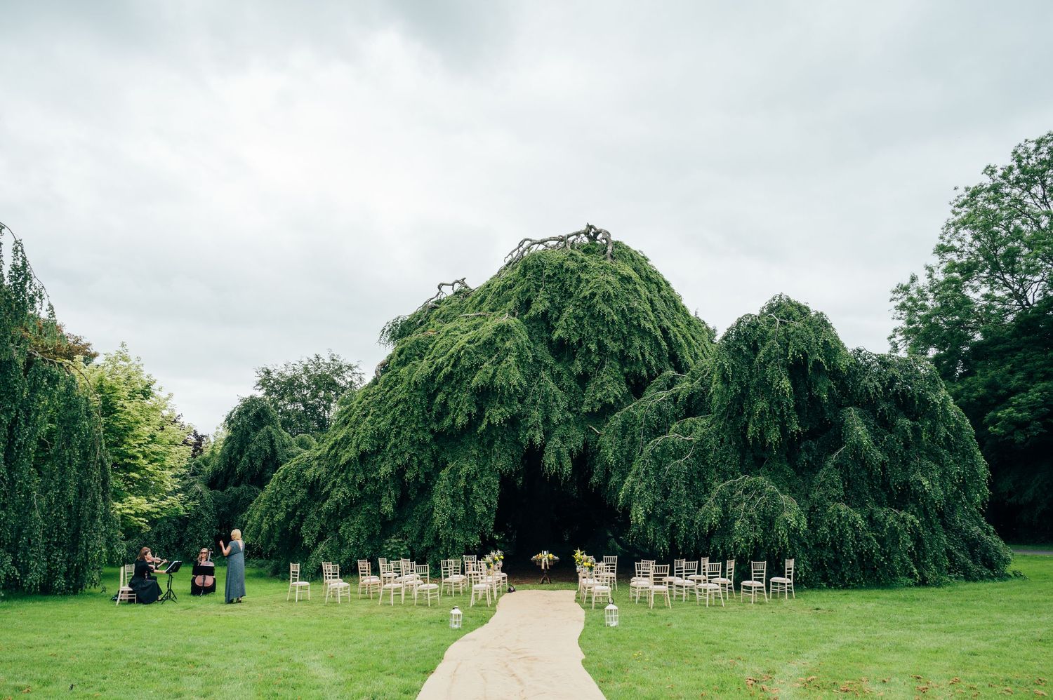 Outdoor wedding ceremony setup with chairs on a grass aisle in a lush garden under the iconic beech at Bellinter house