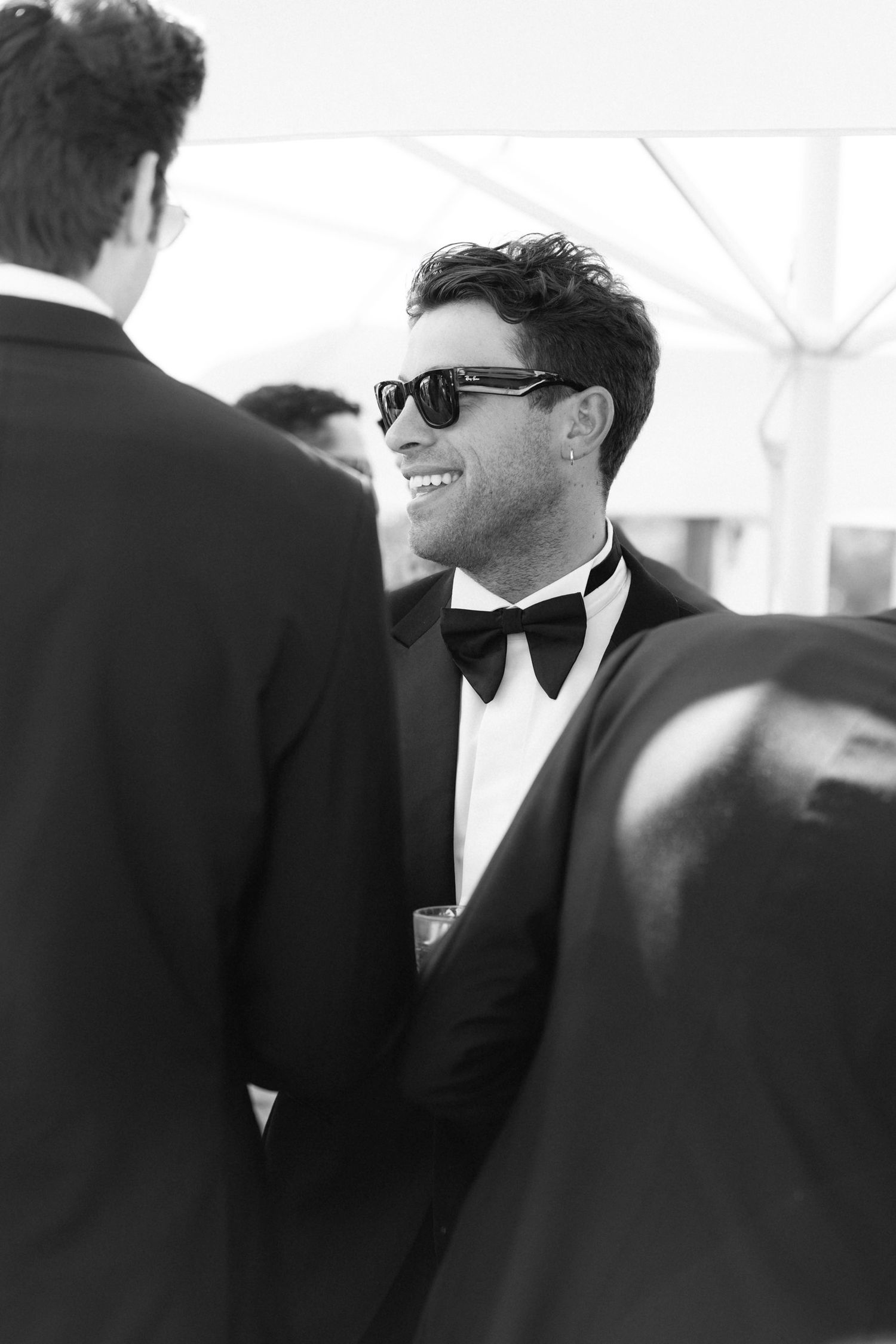 Black and white candid photo of wedding guest smiling at reception.