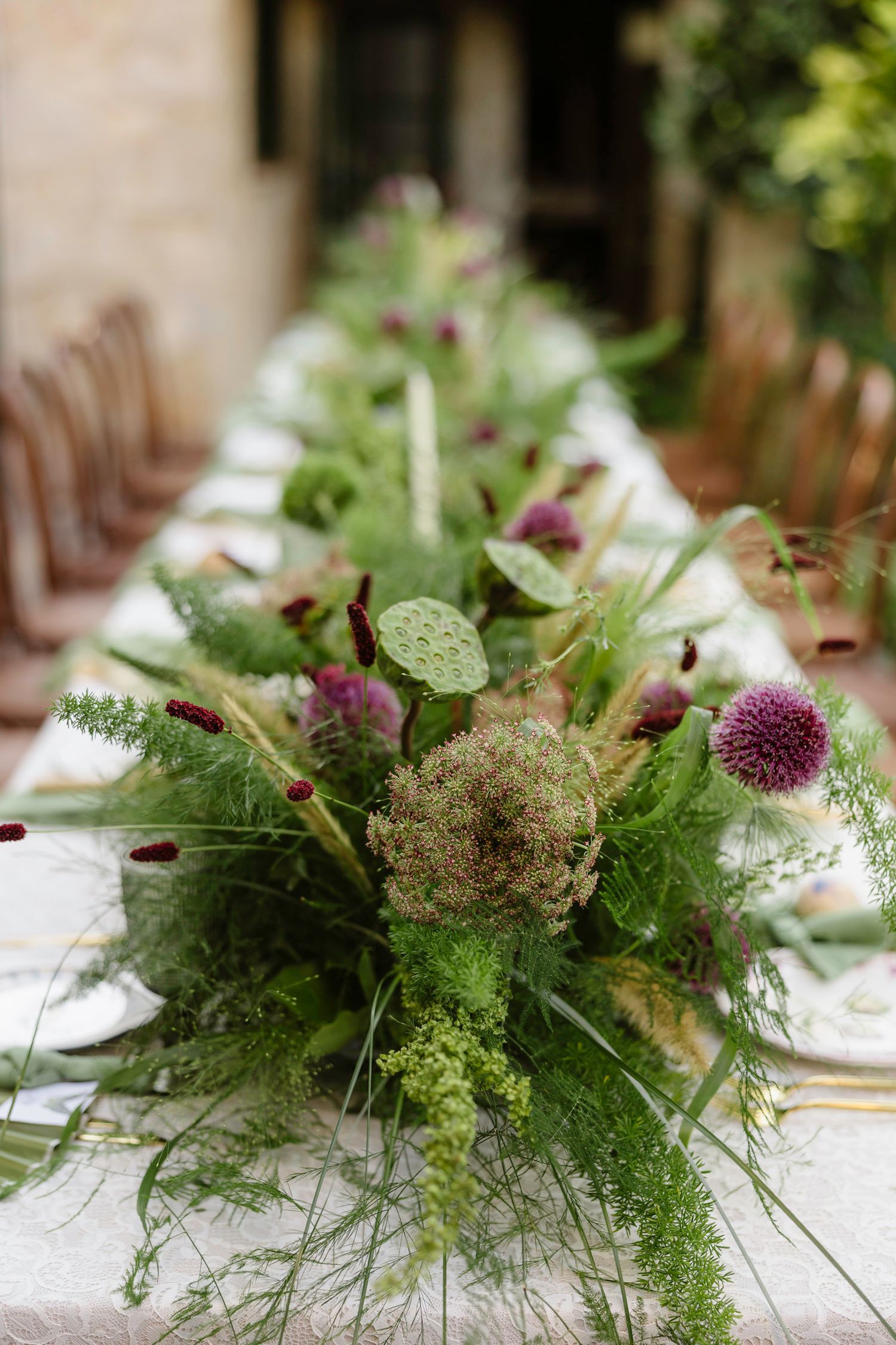 Lush green and purple floral table centerpiece with wild natural elements.