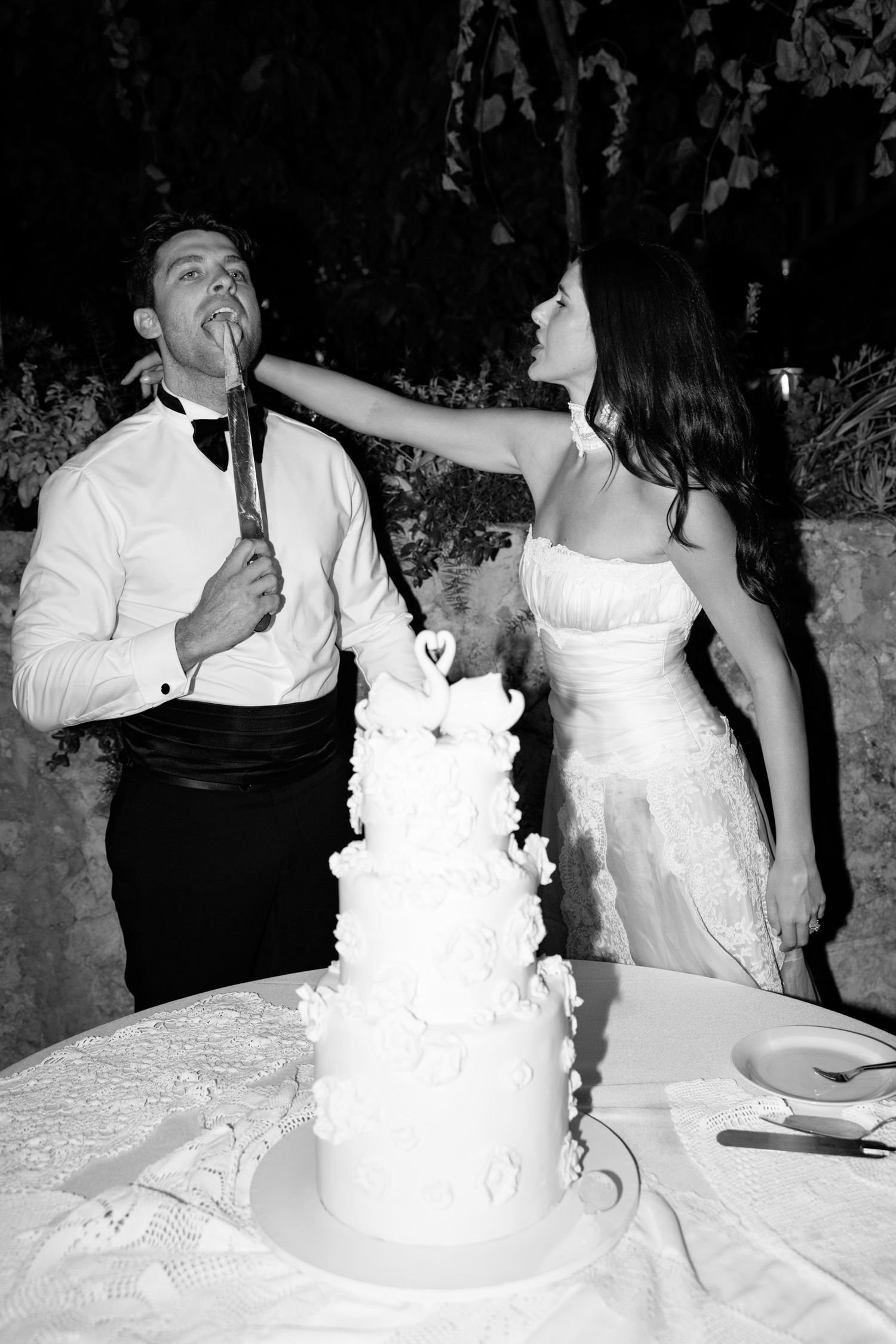 Wedding cake cutting sequence showing white tiered cake with floral decorations. Hvar, Croatia