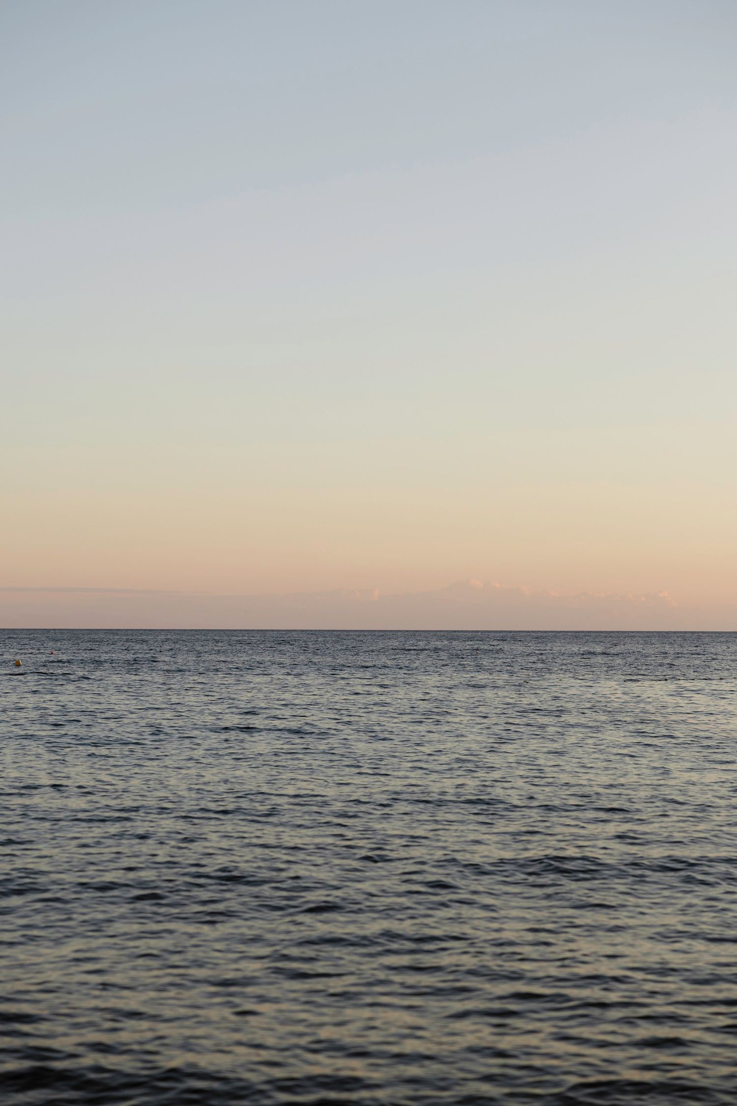 Serene ocean horizon view at dusk with calm waters meeting the sky.