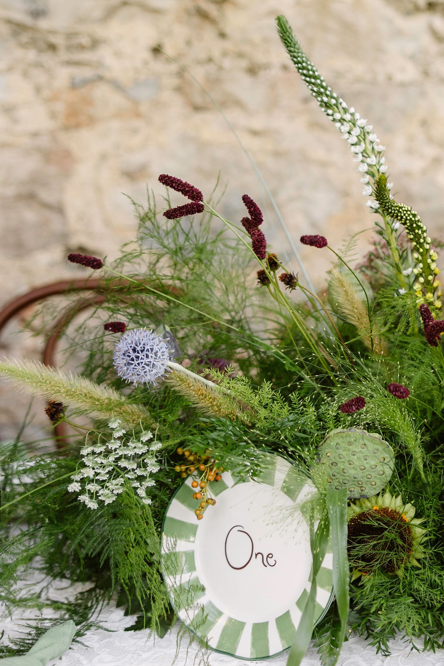Elegant place settings with green foliage and numbered table markers.