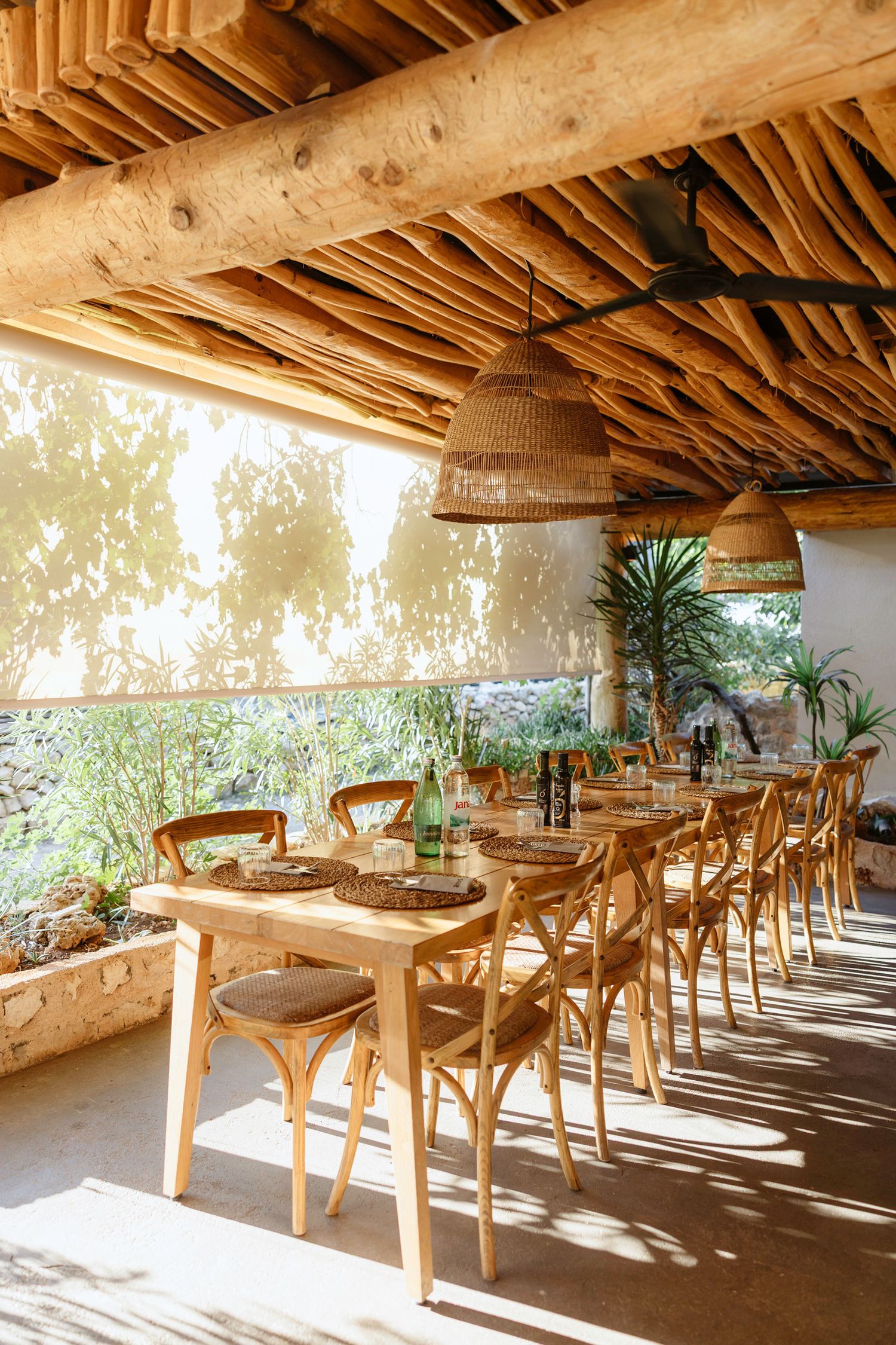 Sunlit restaurant interior with wooden beams and cross-back chairs at dining tables.